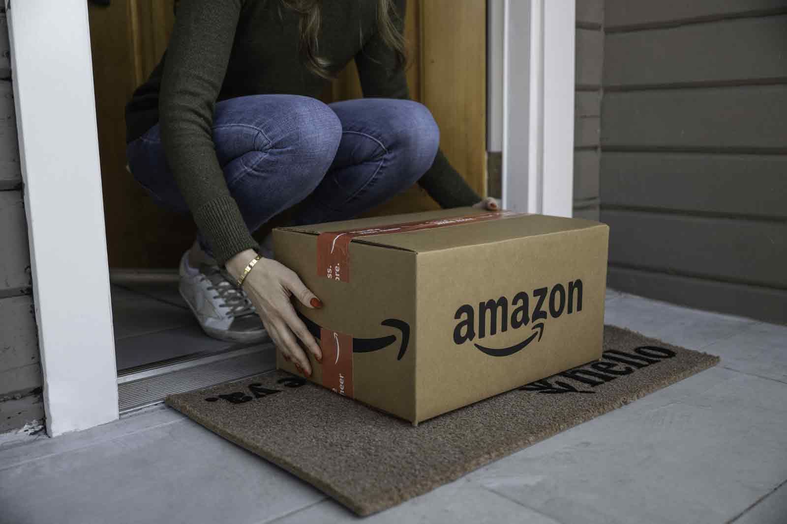 An Amazon box being brought inside from a porch