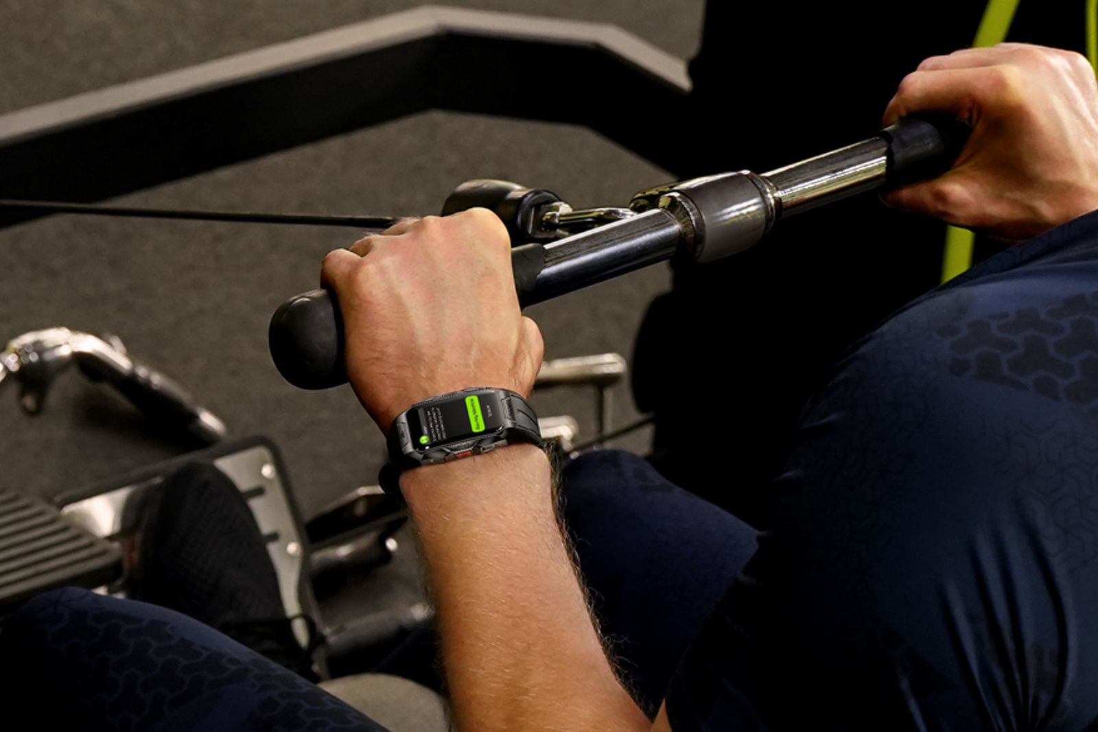 A man uses a rowing machine while wearing a Kospet Tank X1 smartwatch