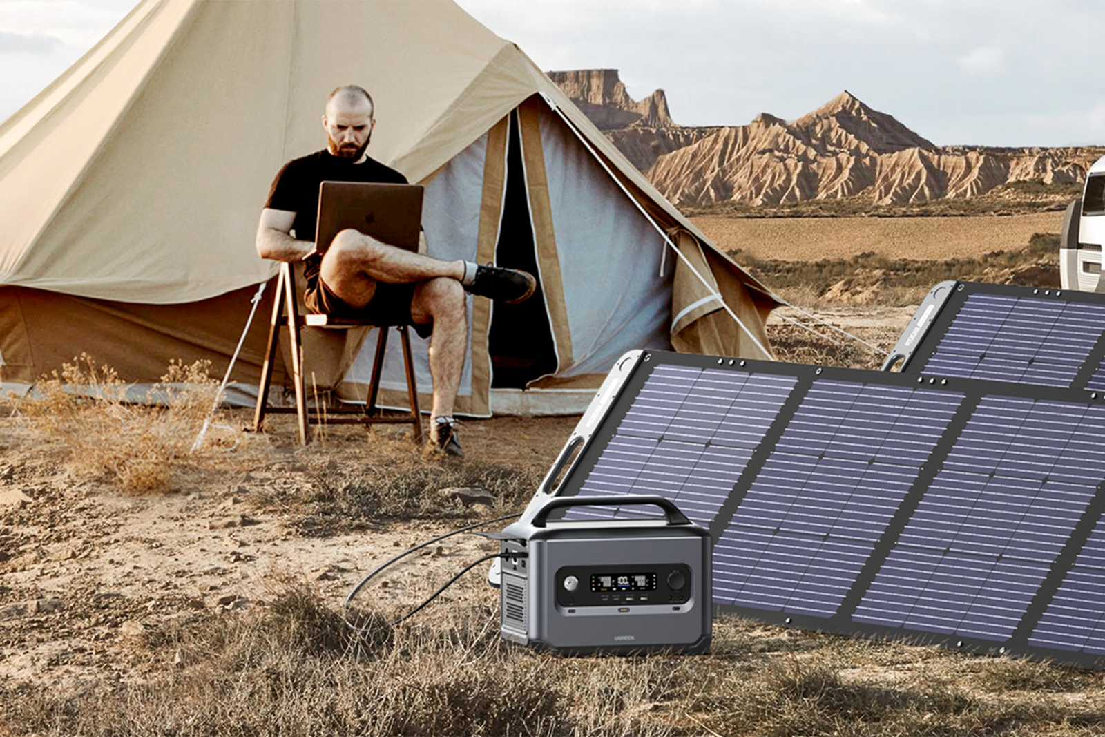 A man uses a laptop while charging the Ugreen PowerRoam 1200 with solar panels