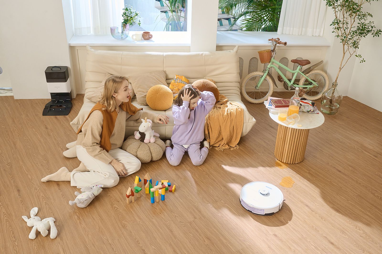 The Roborock S8+ vacuum cleans up spills while a girl and her mother watch