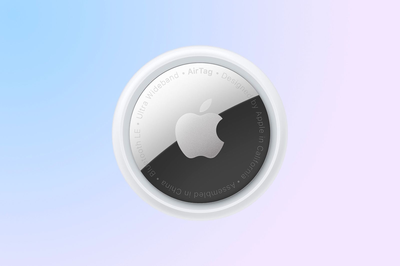 A circular Apple AirTag lying face up with it's silver back facing the camera over a bluish-pink background. 