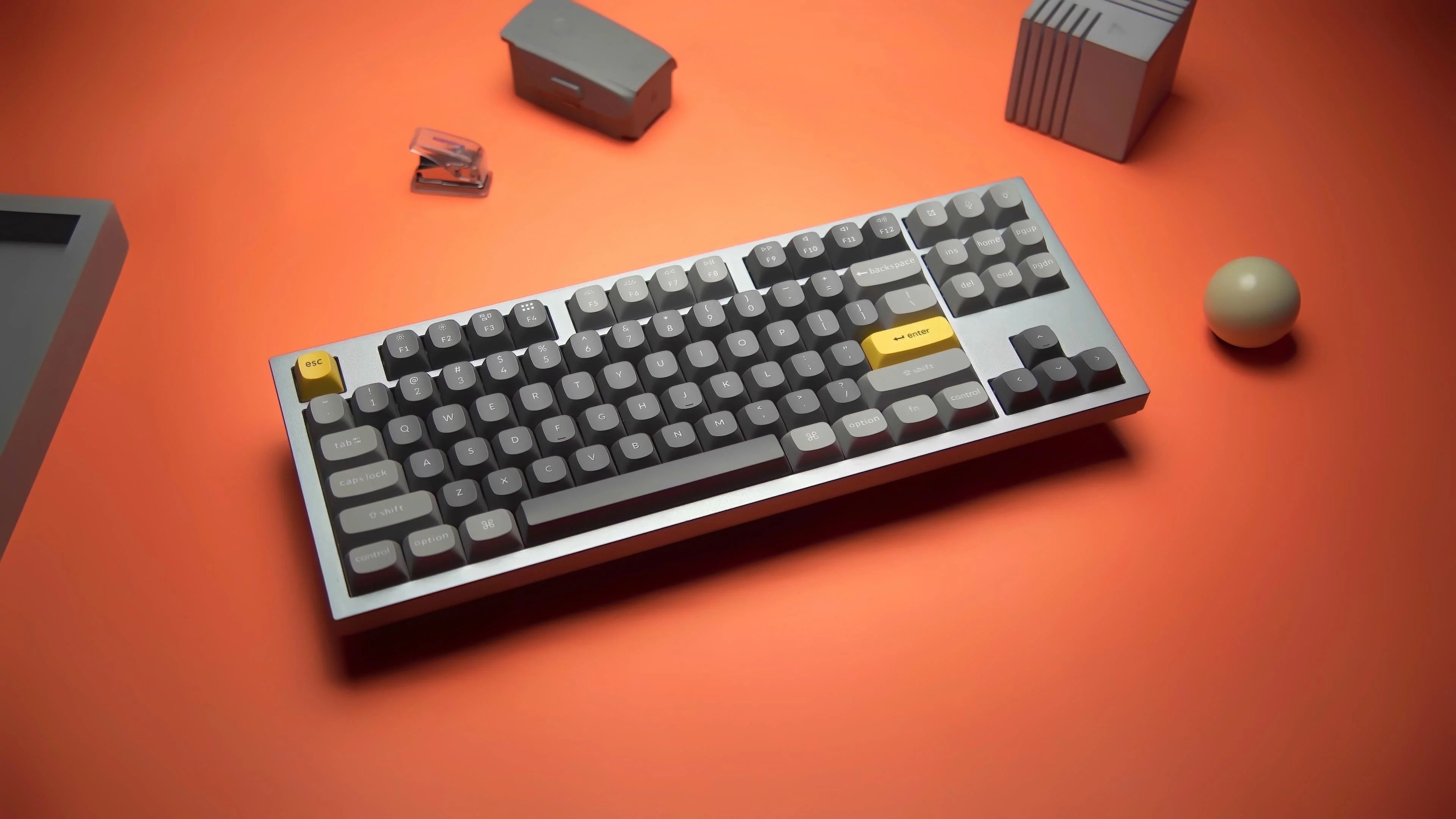 A grey and silver mechanical keyboard on an orange background.
