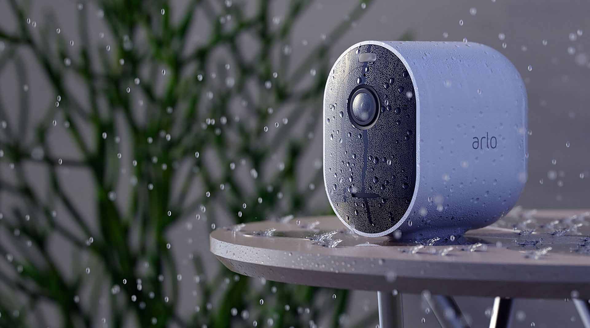 Arlo Pro 4 Spotlight Camera sitting on a surface covered in raindrops.