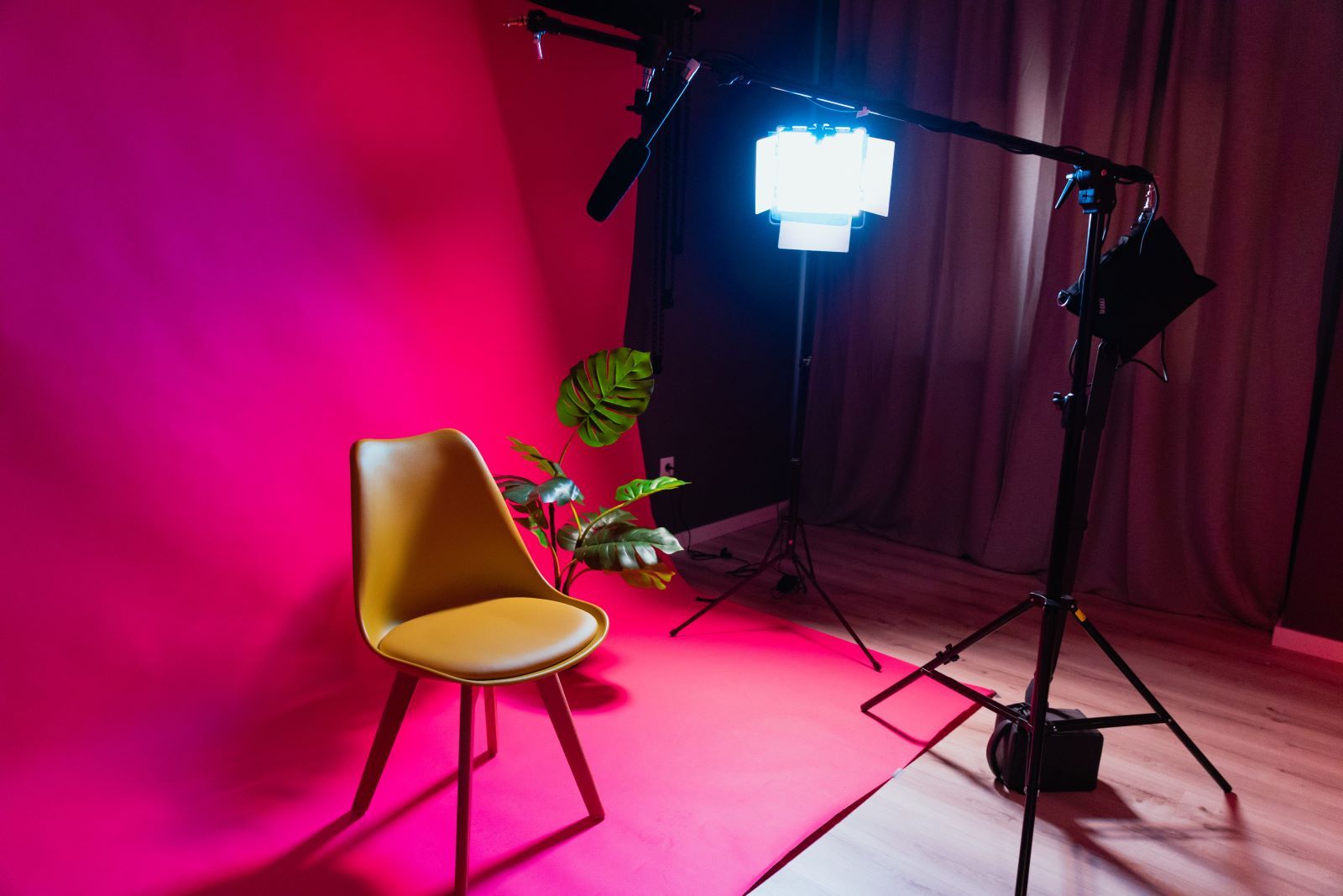Video and teleprompter set up with pink background and yellow chair
