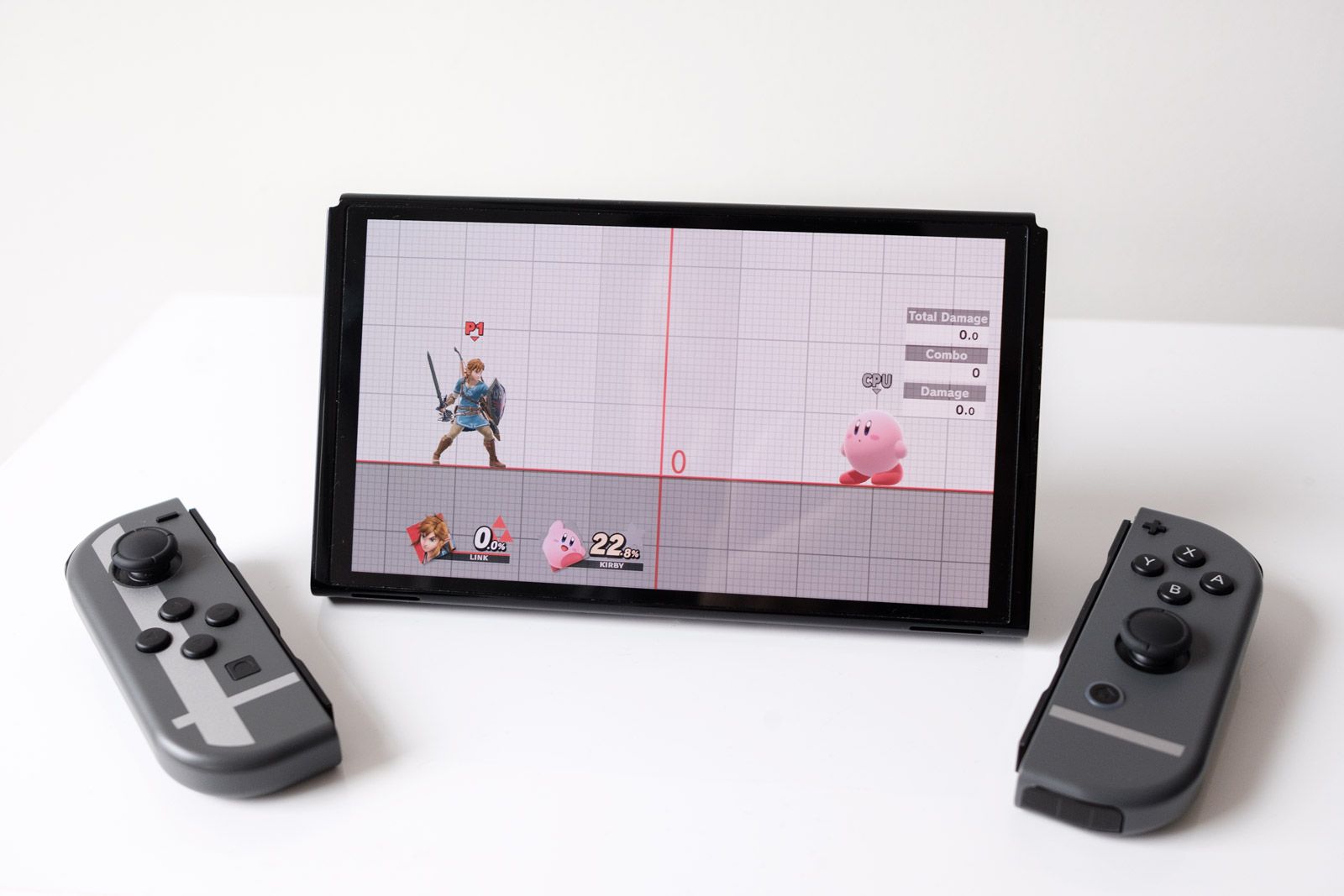 A Nintendo Switch OLED with Super Smash Bros. Ultimate on screen. Link and Kirby prepare to battle. 