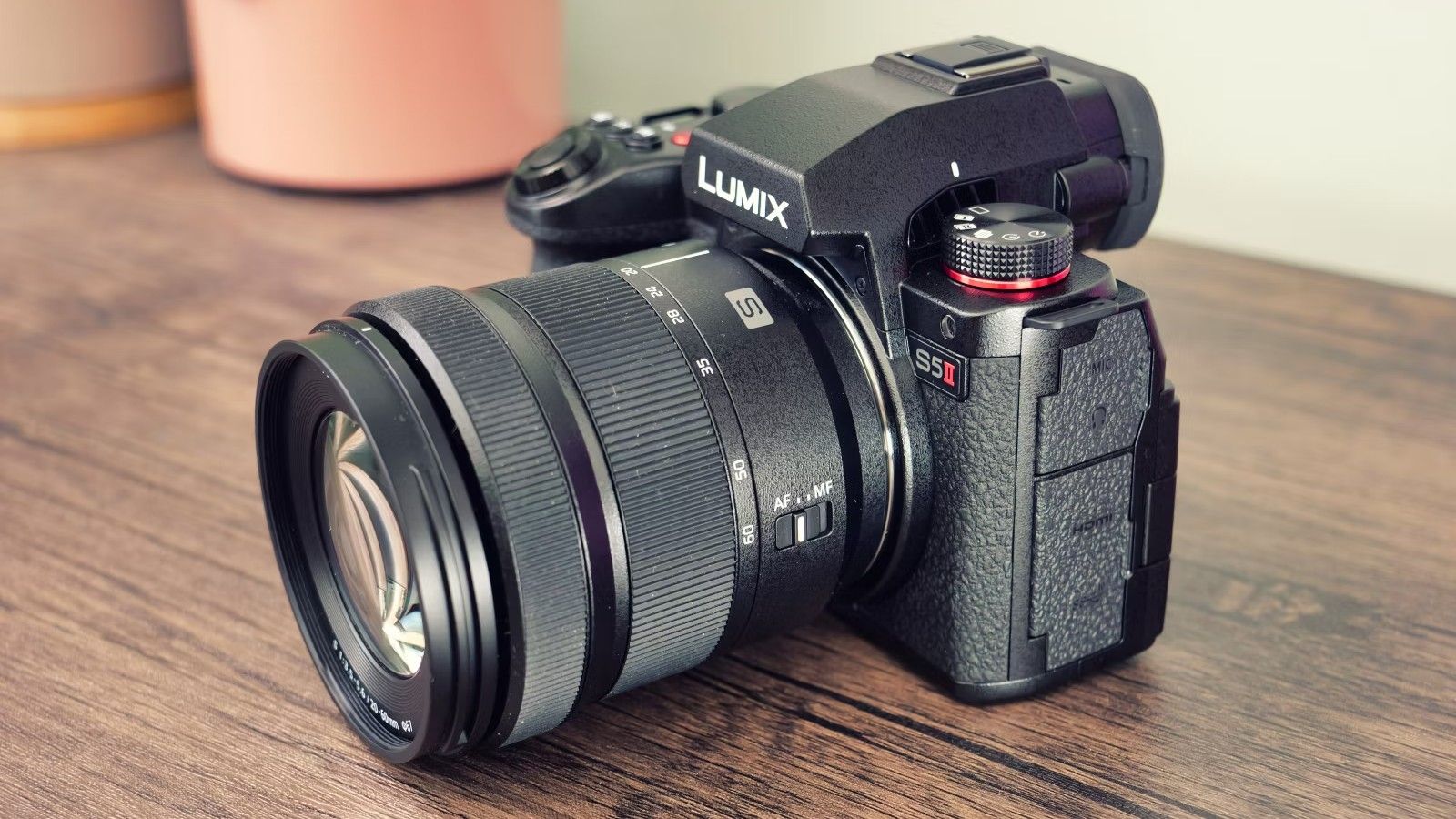 A Panasonic Lumix S5II camera with kit lens sits on a wood table.