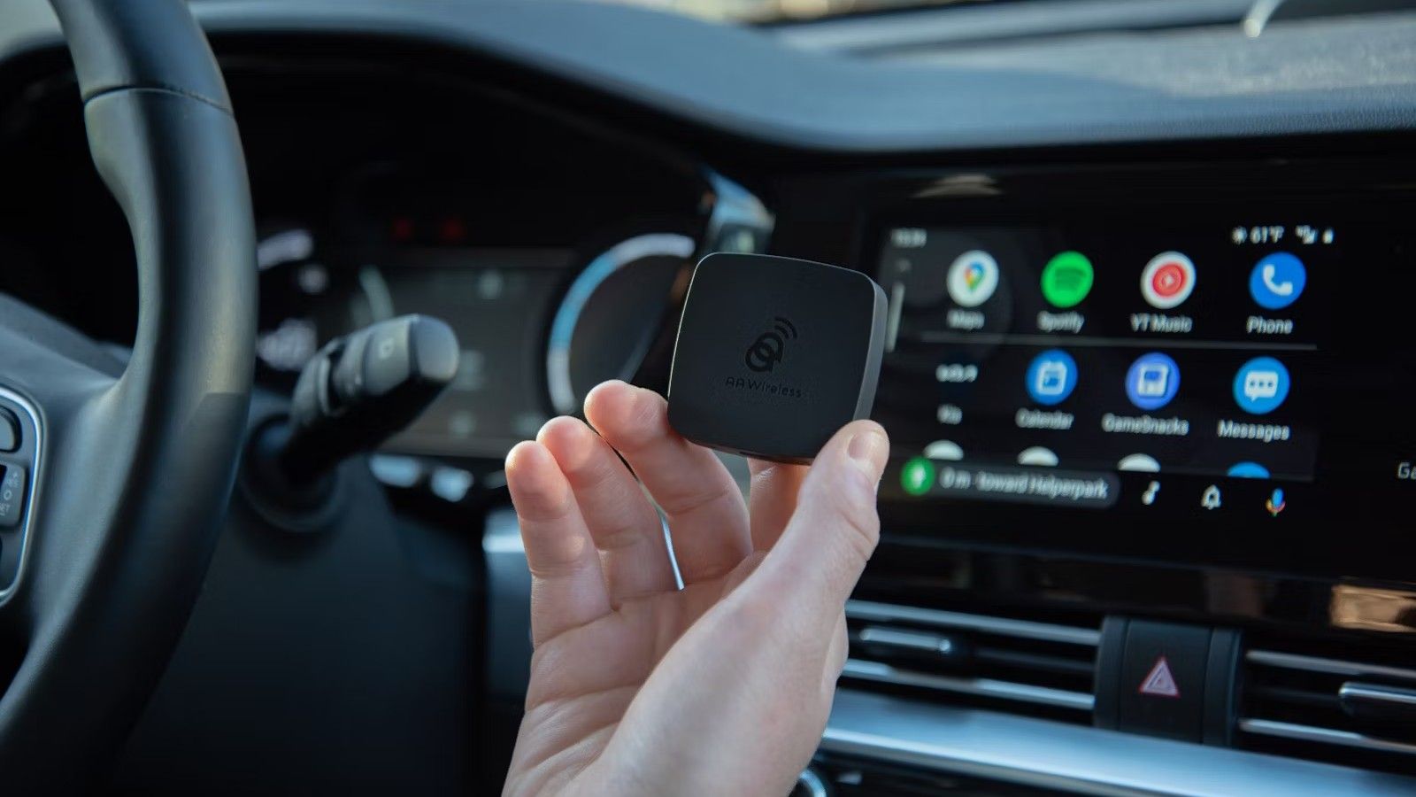 A person holds an AAWireless Android Auto adapter in their hand
