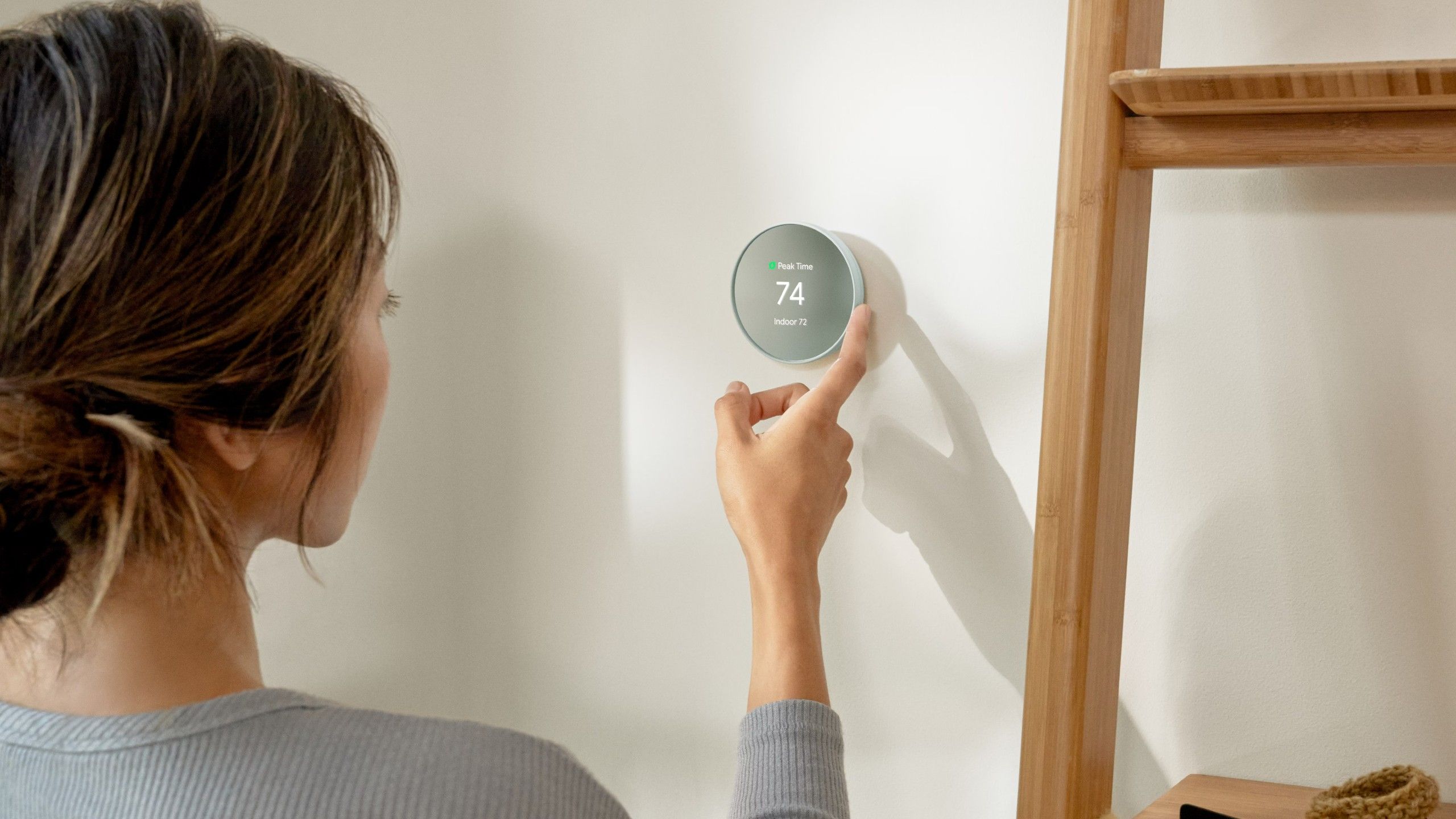 A woman sets the temperature with a Nest Thermostat