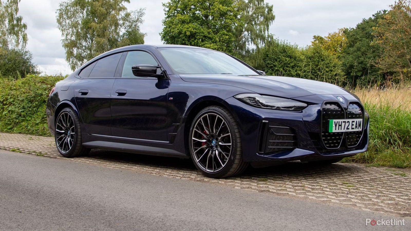 Um BMW i4 EV azul está estacionado na beira da estrada