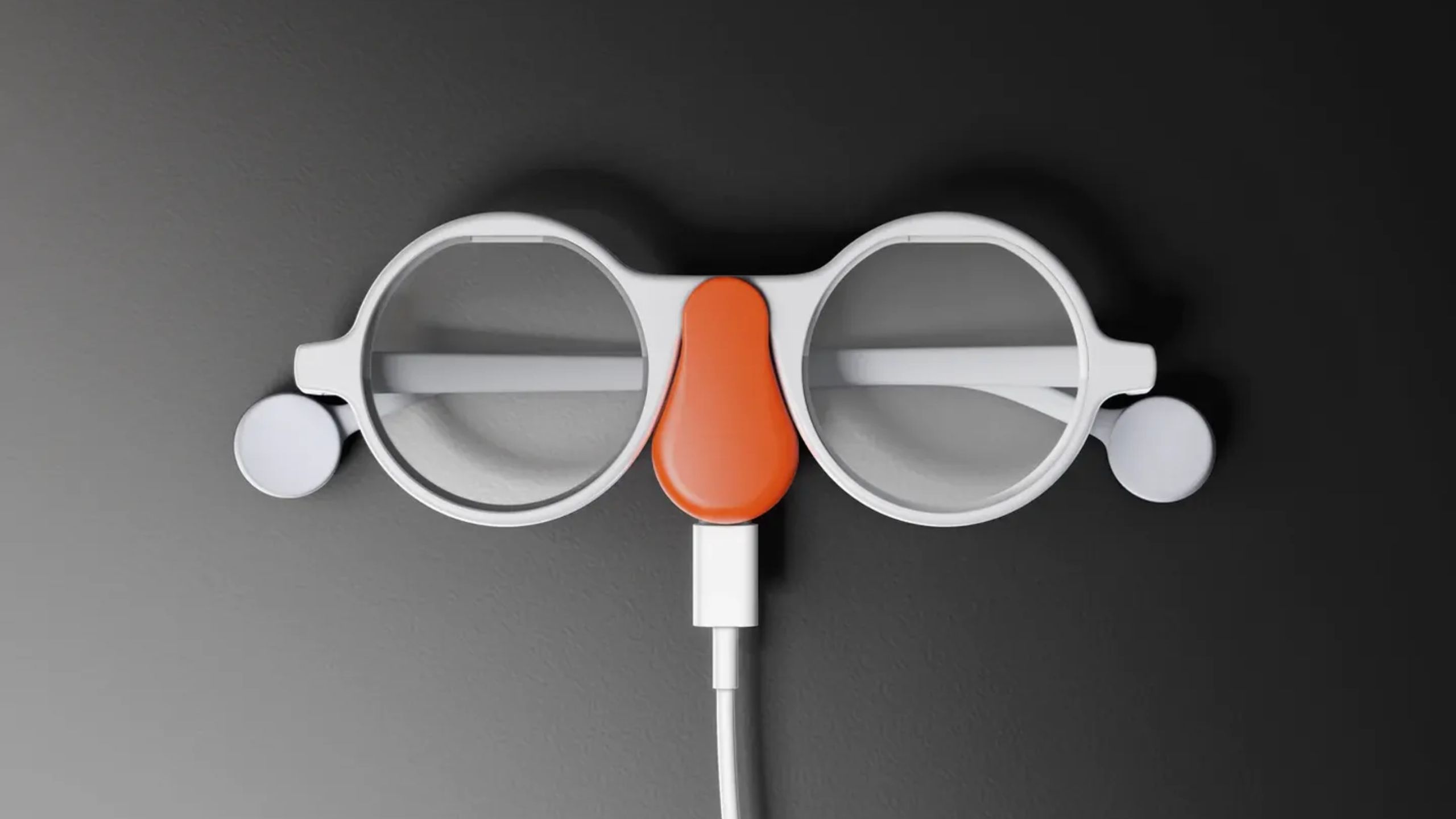 Round AR glasses with a charging clip attached.