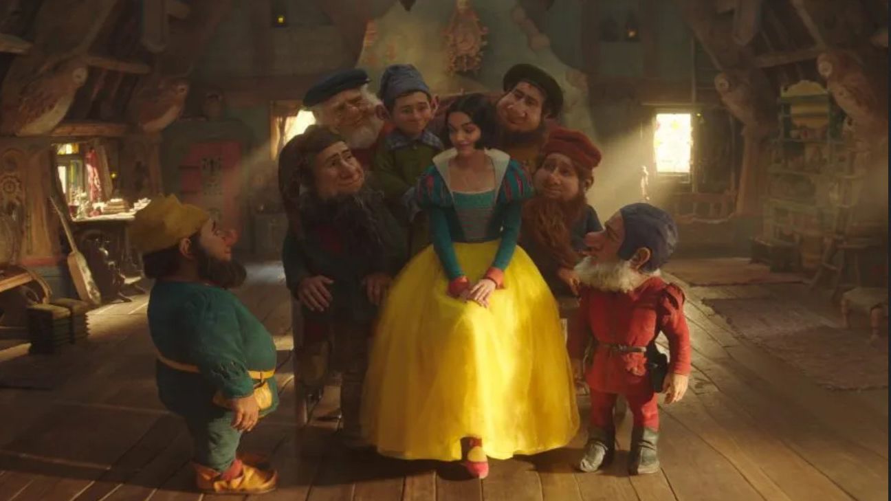 Actress Rachel Zegler as Snow White surrounding by seven dwarfs in the live action Disney movie