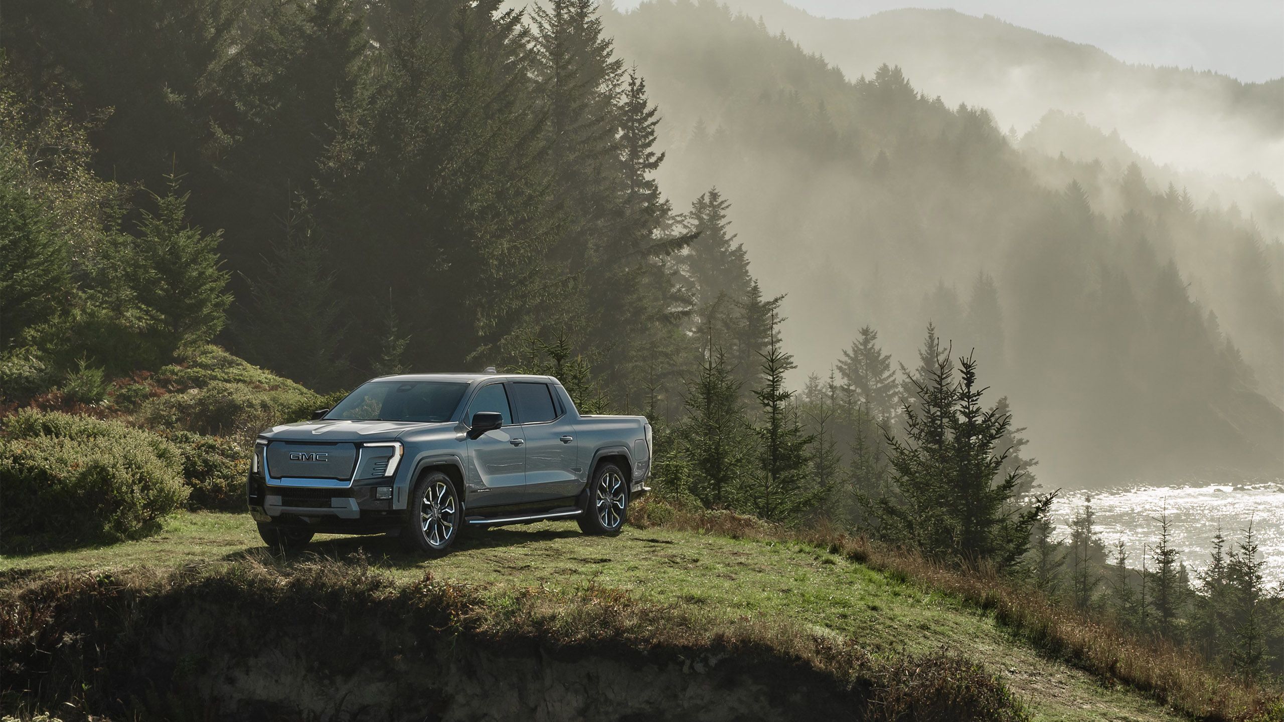 The 2024 GMC Sierra EV Denali Edition 1 sits on a forested hill