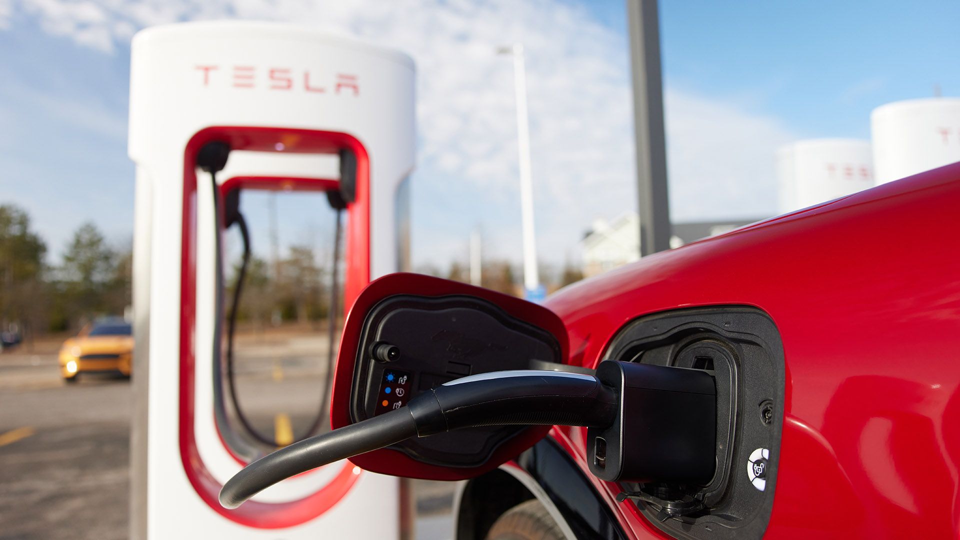 A Ford Mustang Mach-E charges at a Tesla Fast Charging station.