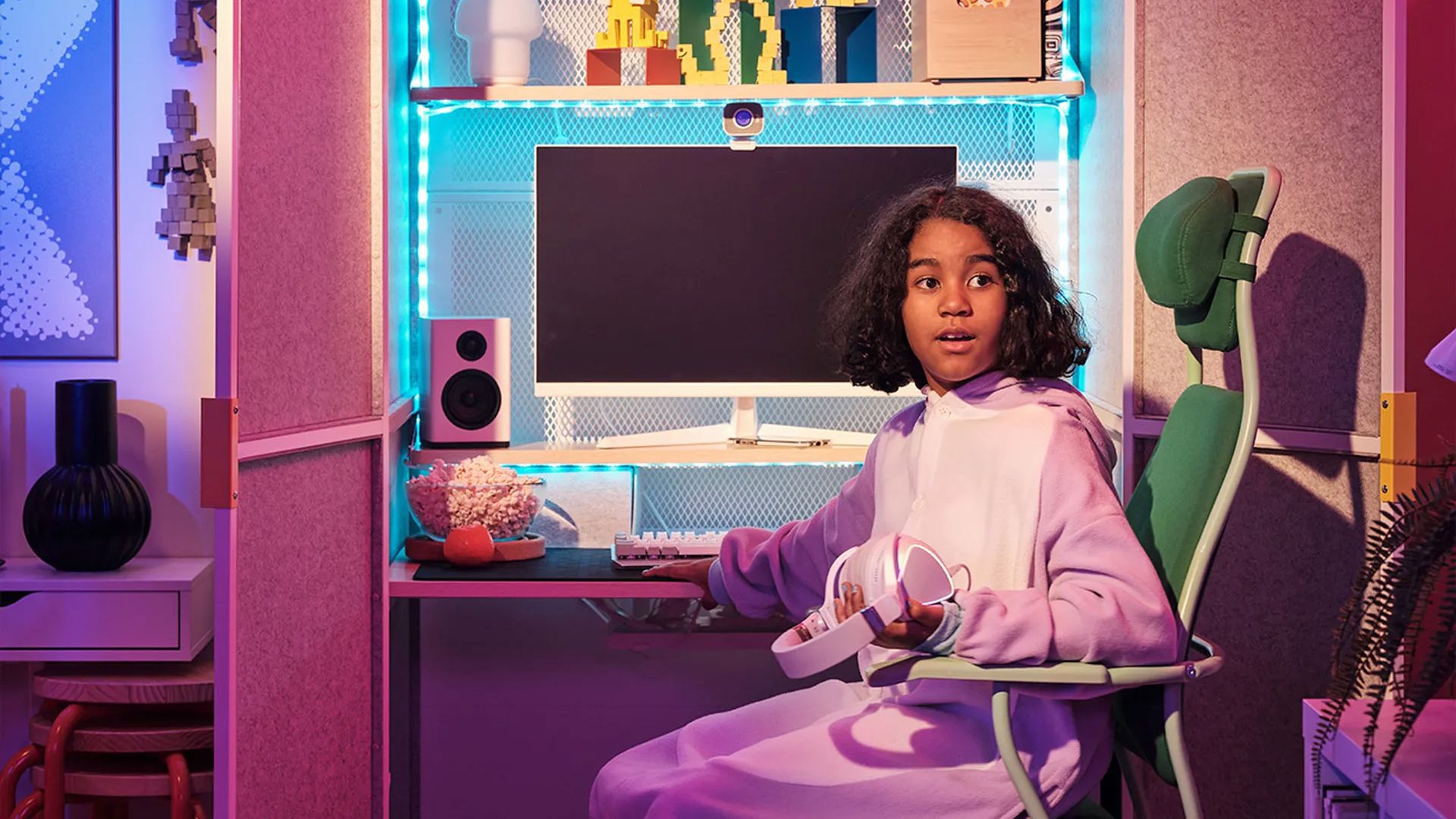 A girl sits in front of an Ikea Brannboll gaming station.