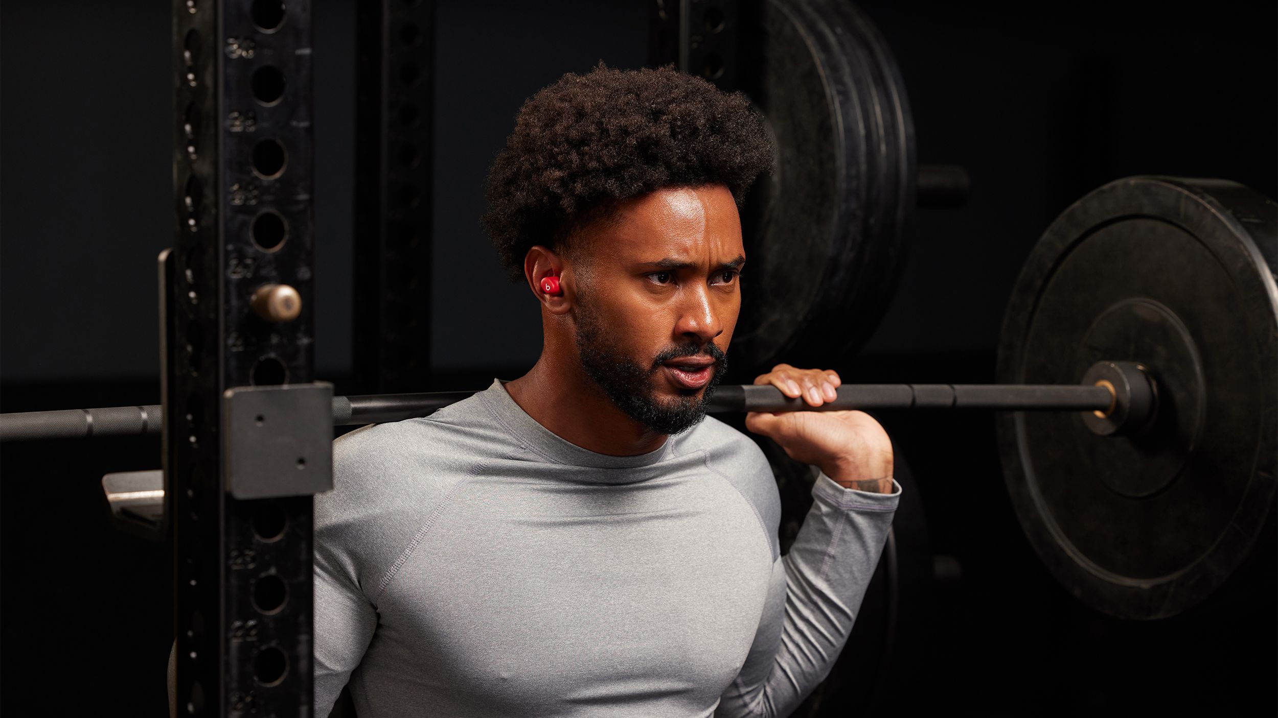 A man wears the Beats Solo Buds while squatting in a gym.