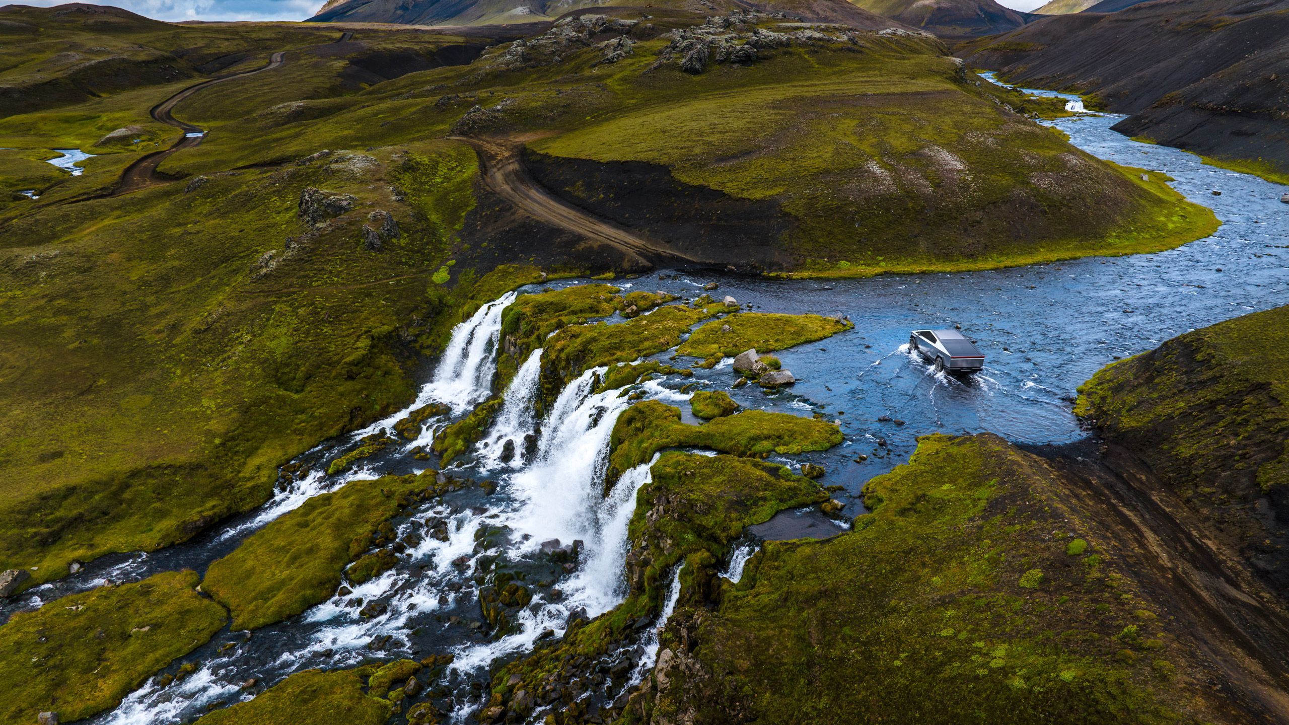 A Tesla Cybertruck crosses a river in a tundra