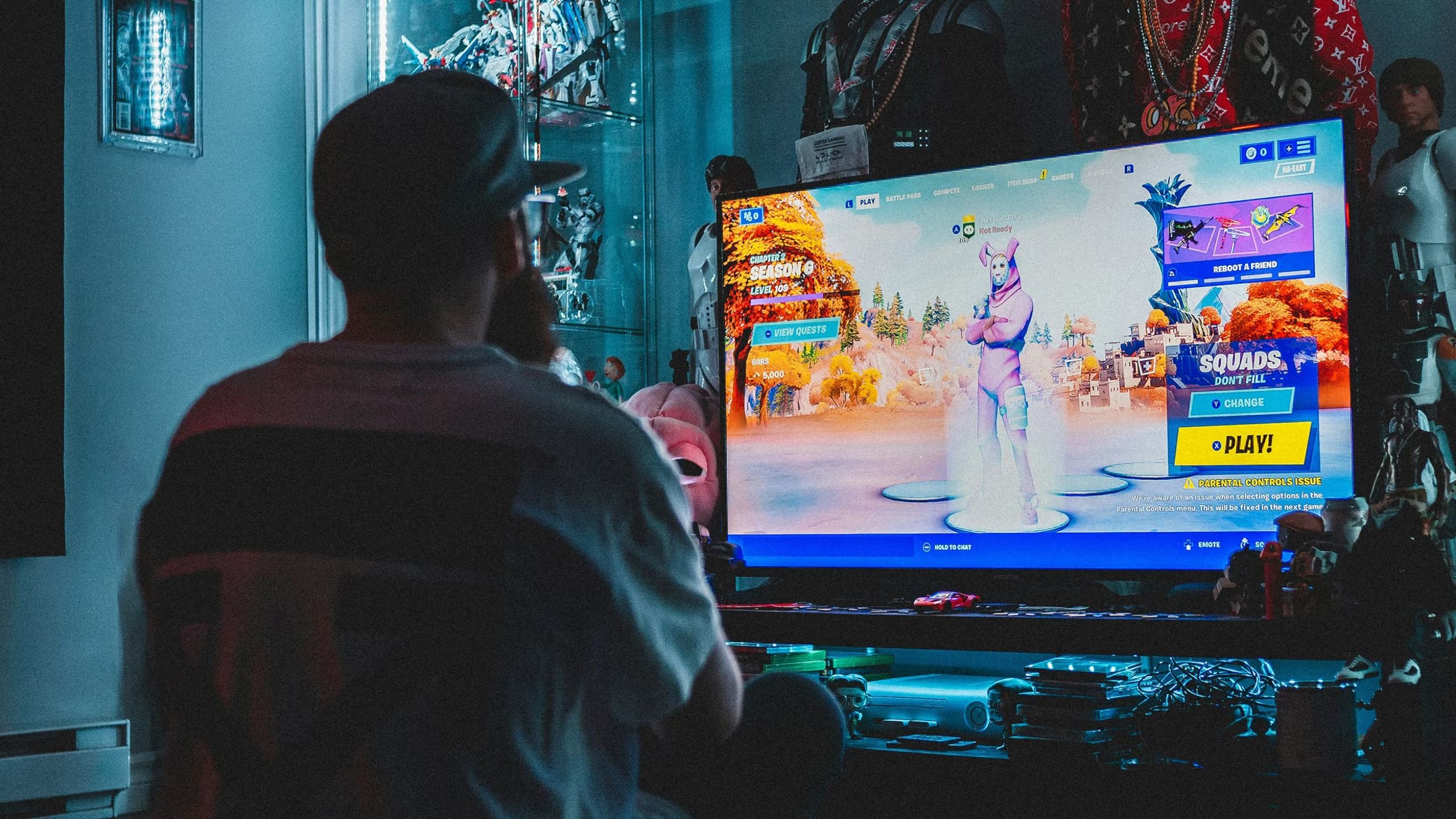 Person sitting in front of their monitor in a dark room playing Fortnite. 
