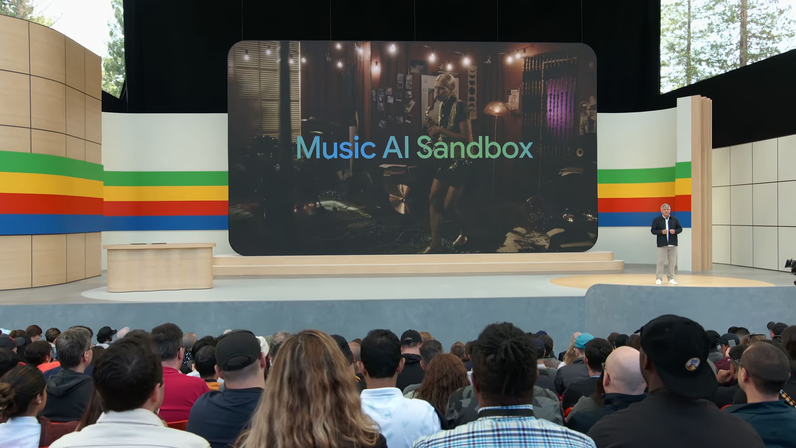 A crowd looks at a stage with a screen displaying Google's Music AI Sandbox.