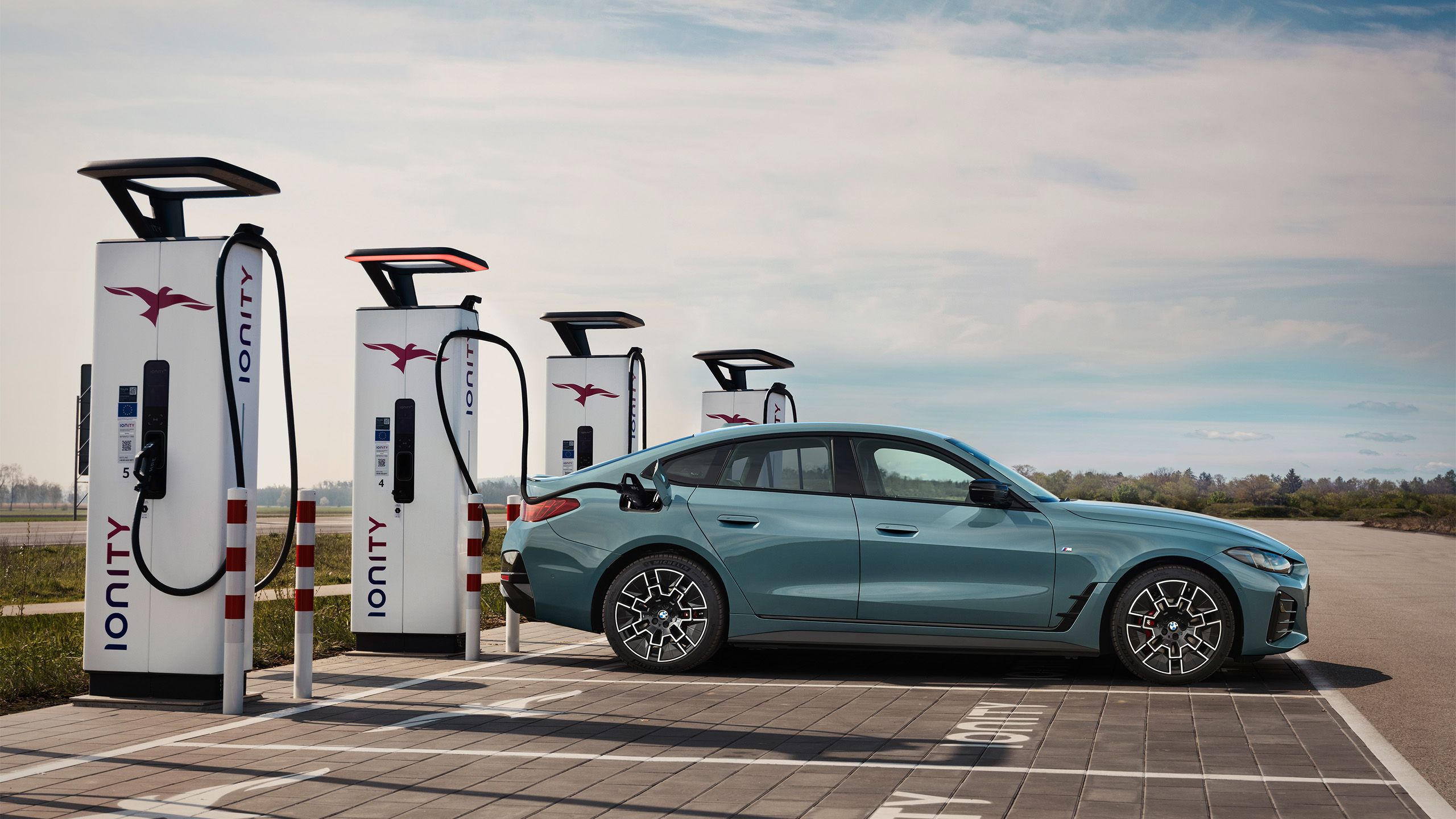 A 2025 BMW i4 M50 xDrive sits at a charging station