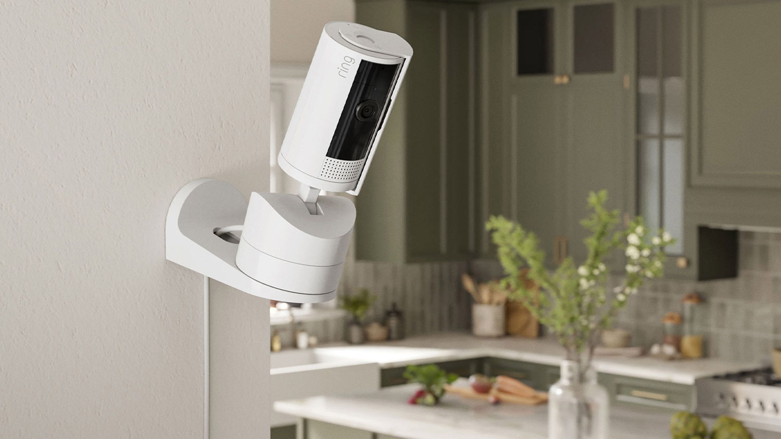 A white Ring Pan Tilt Indoor Cam sits on a kitchen wall