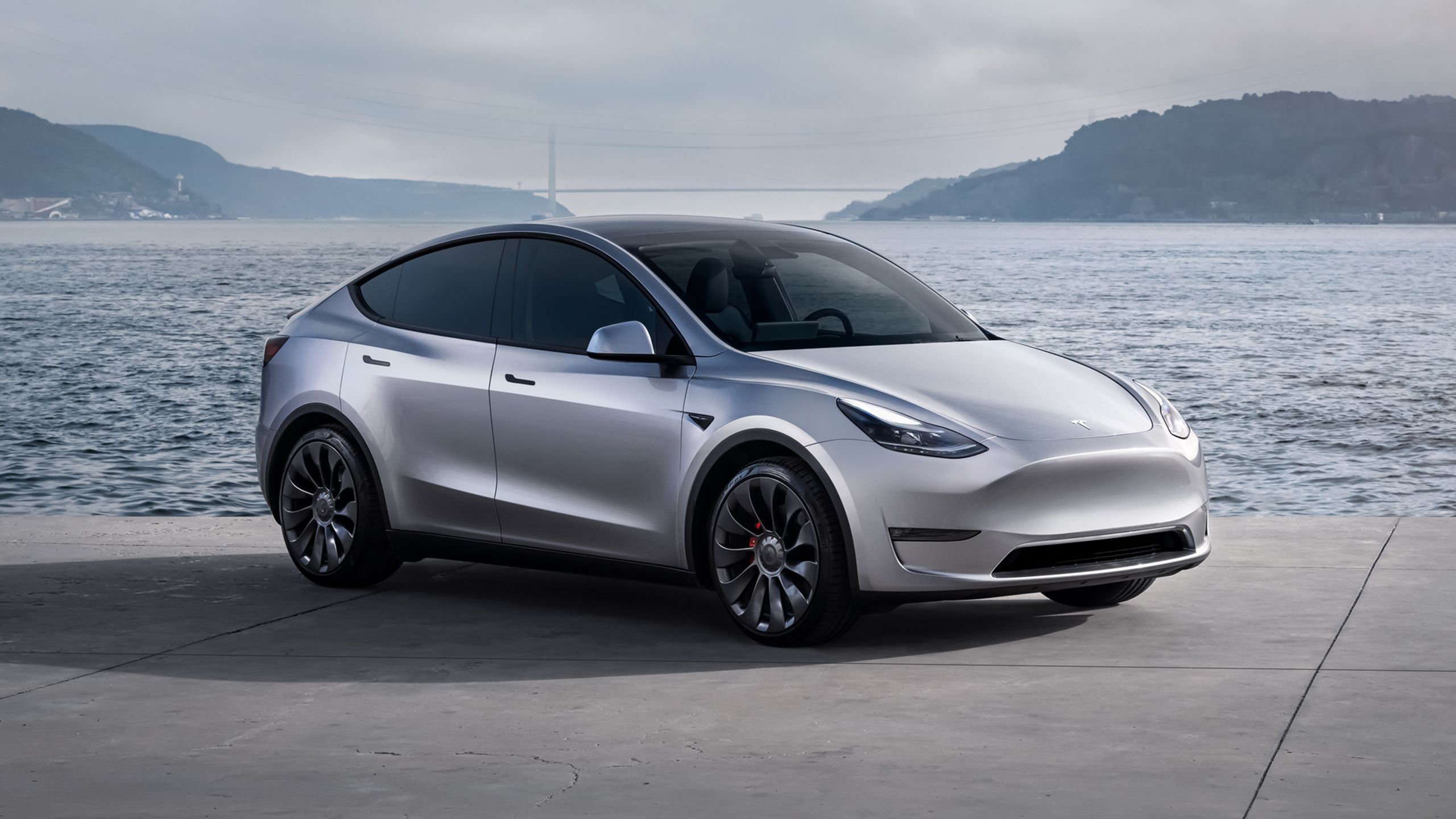 Tesla Model Y in front of a bay on a cloudy day.