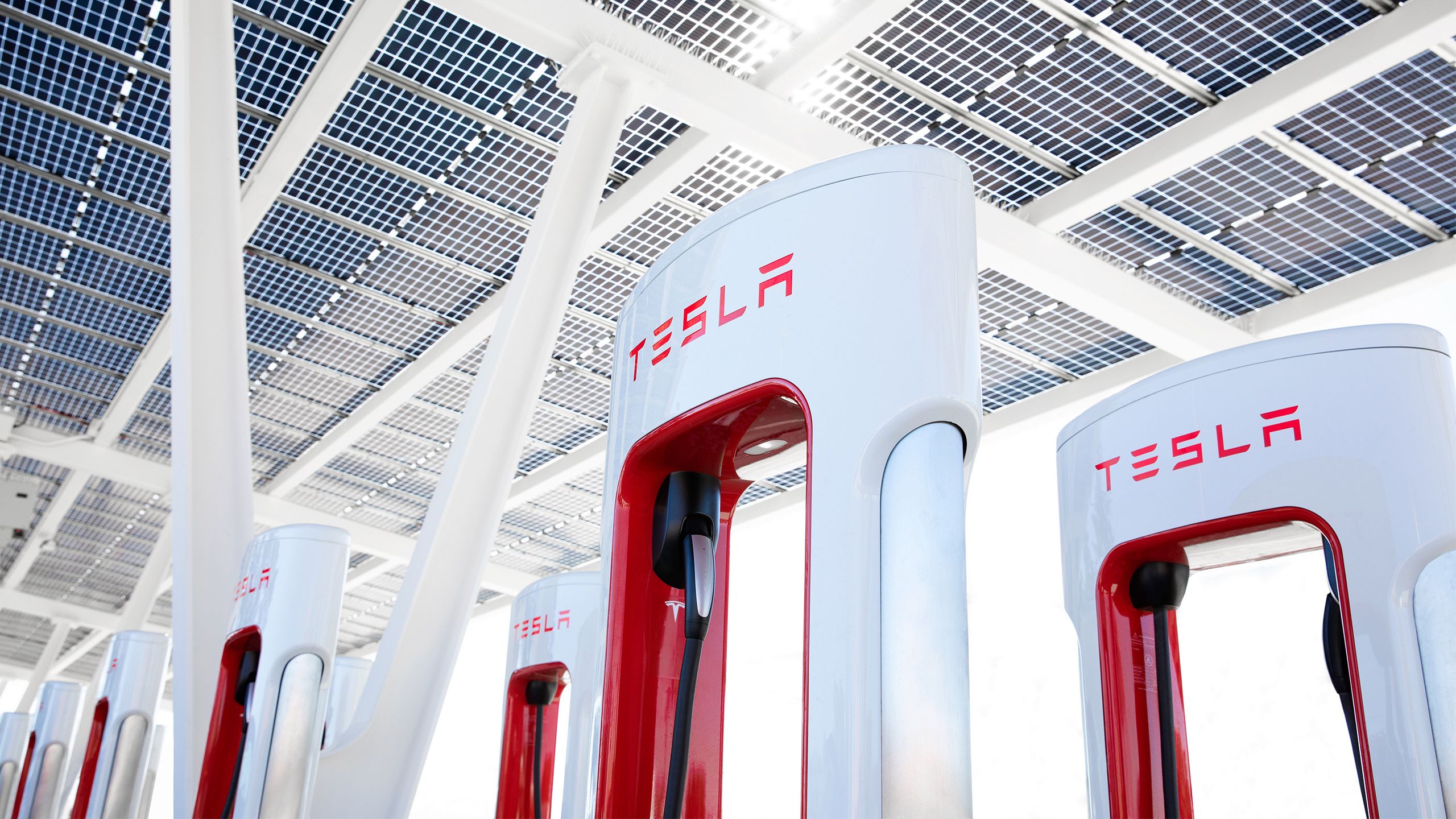 A row of Tesla Superchargers under a solar roof