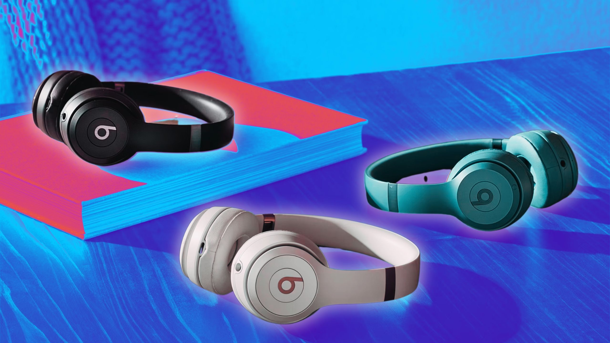 The black, pink, and blue Beats Solo 4 headphones are on a table.