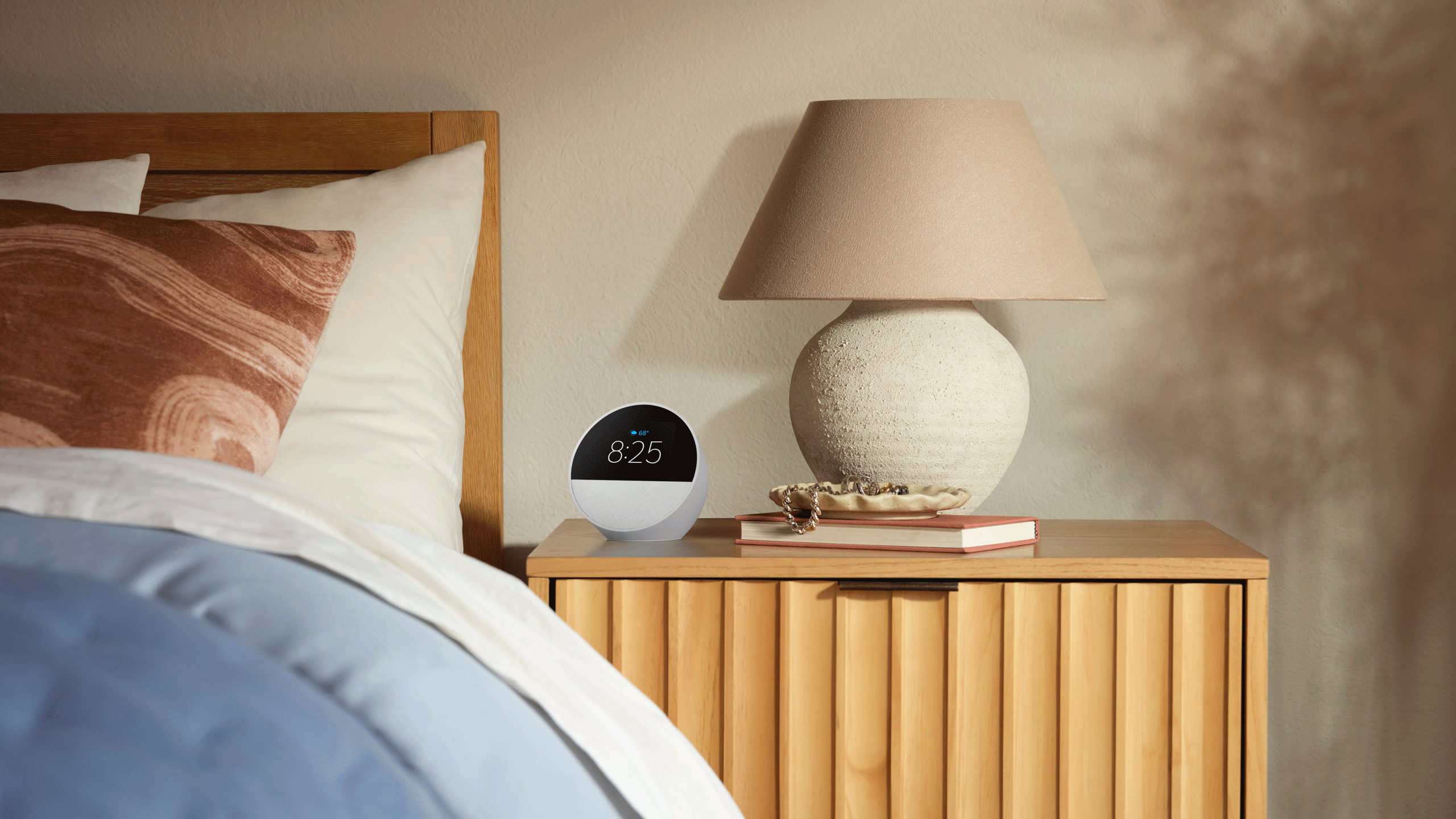 Un Echo Spot blanco se encuentra sobre una mesita de noche.