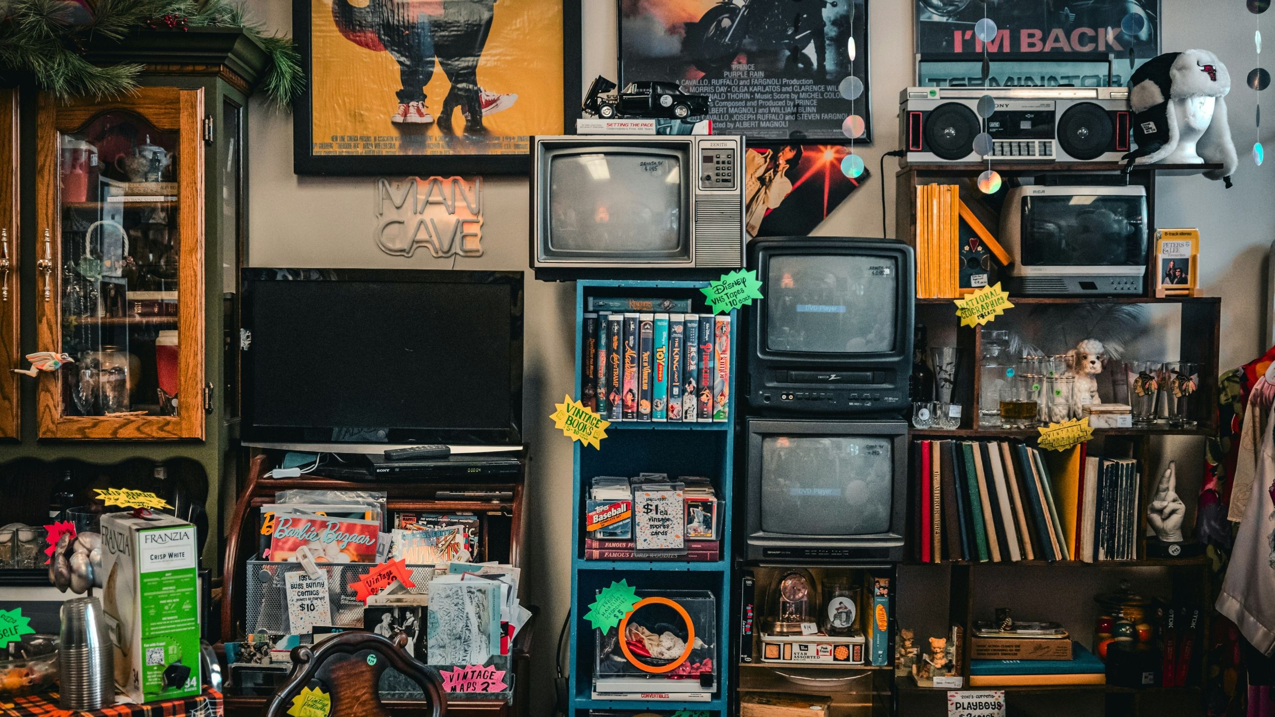 Thrift store wall with TVs and DVDs on shelves. 