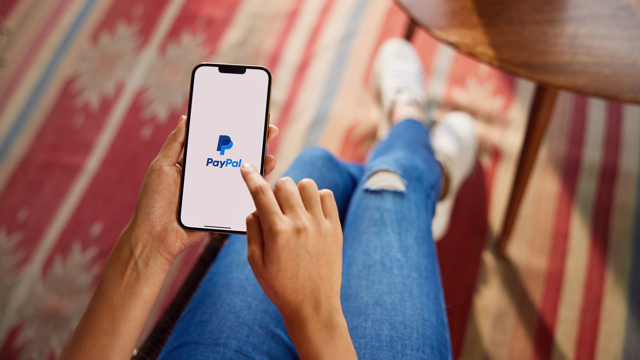 A person holding a smartphone with the PayPal app