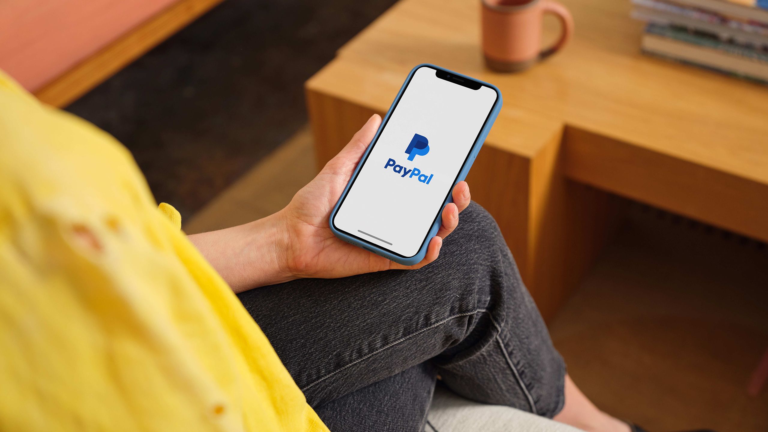 A woman holding a smartphone with the PayPal app