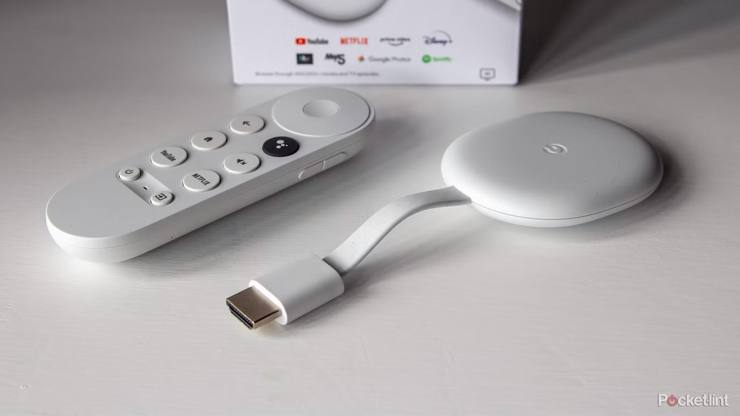 A Chromecast with Google TV stands on a white table