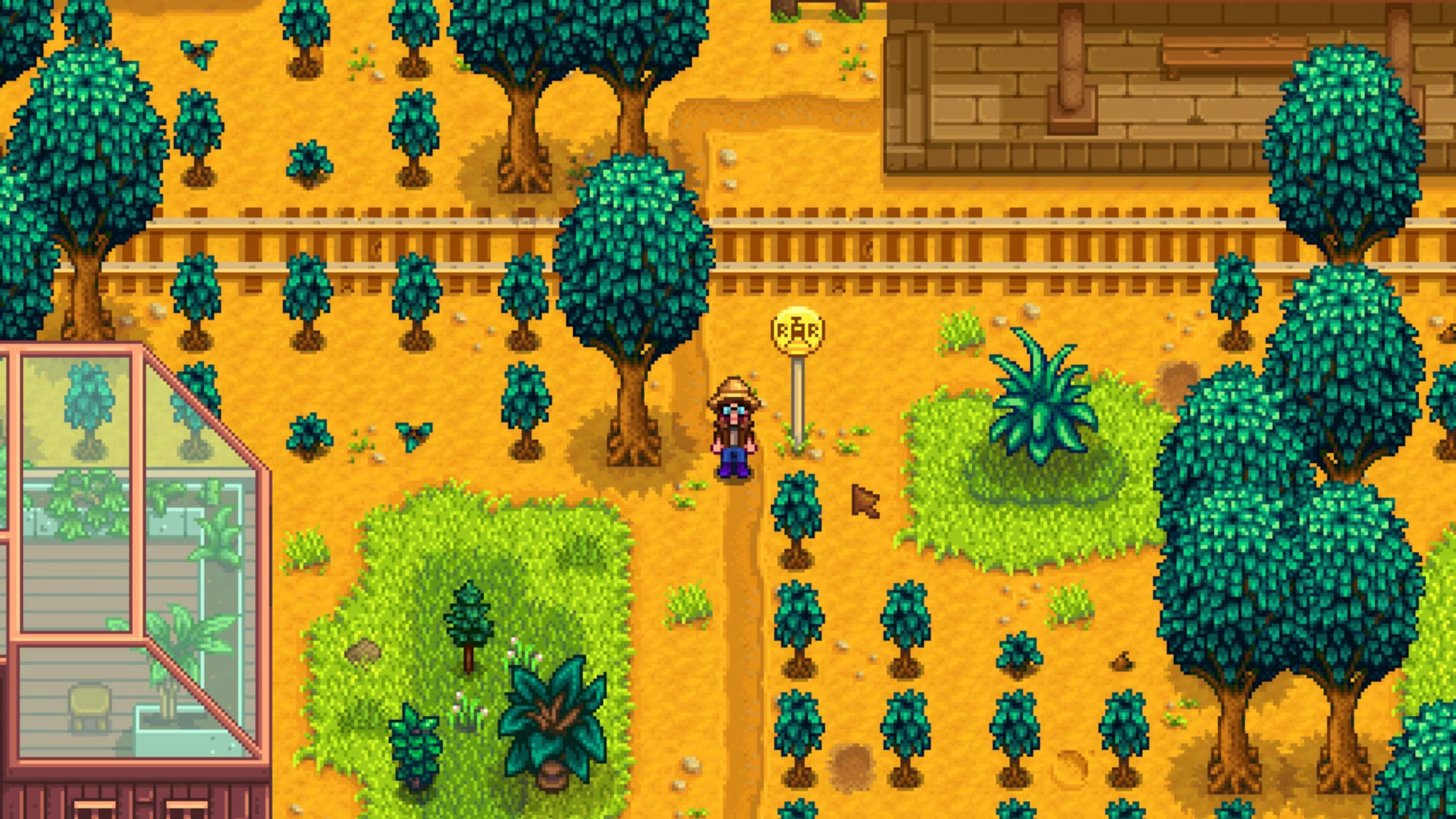 a person beside trees and train tracks in stardew valley