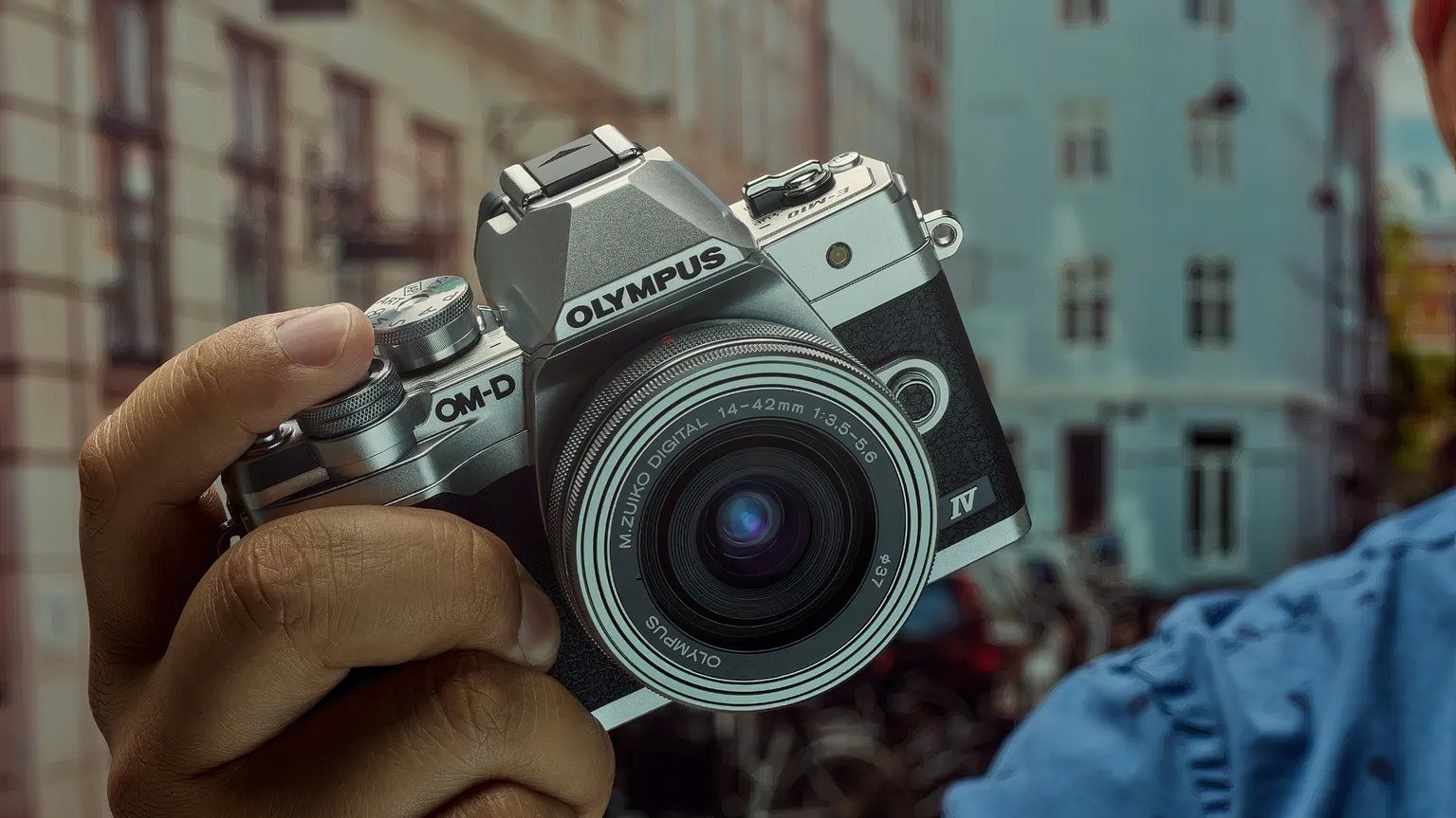 The Olympus OM-D E-M1 Mark IV is held in a hand