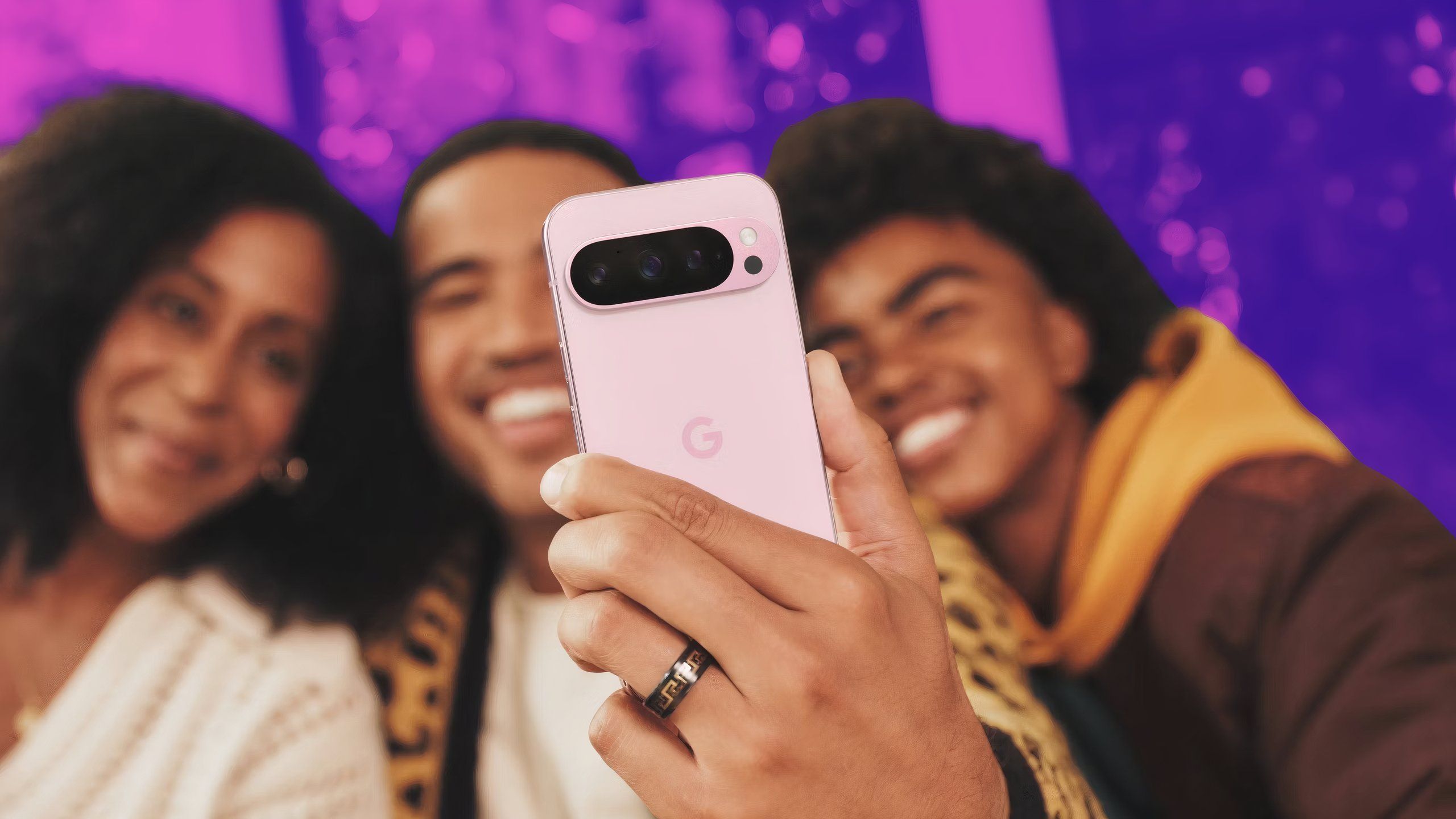 People taking a group selfie with the Rose Quartz Pixel 9 Pro against a colored background.