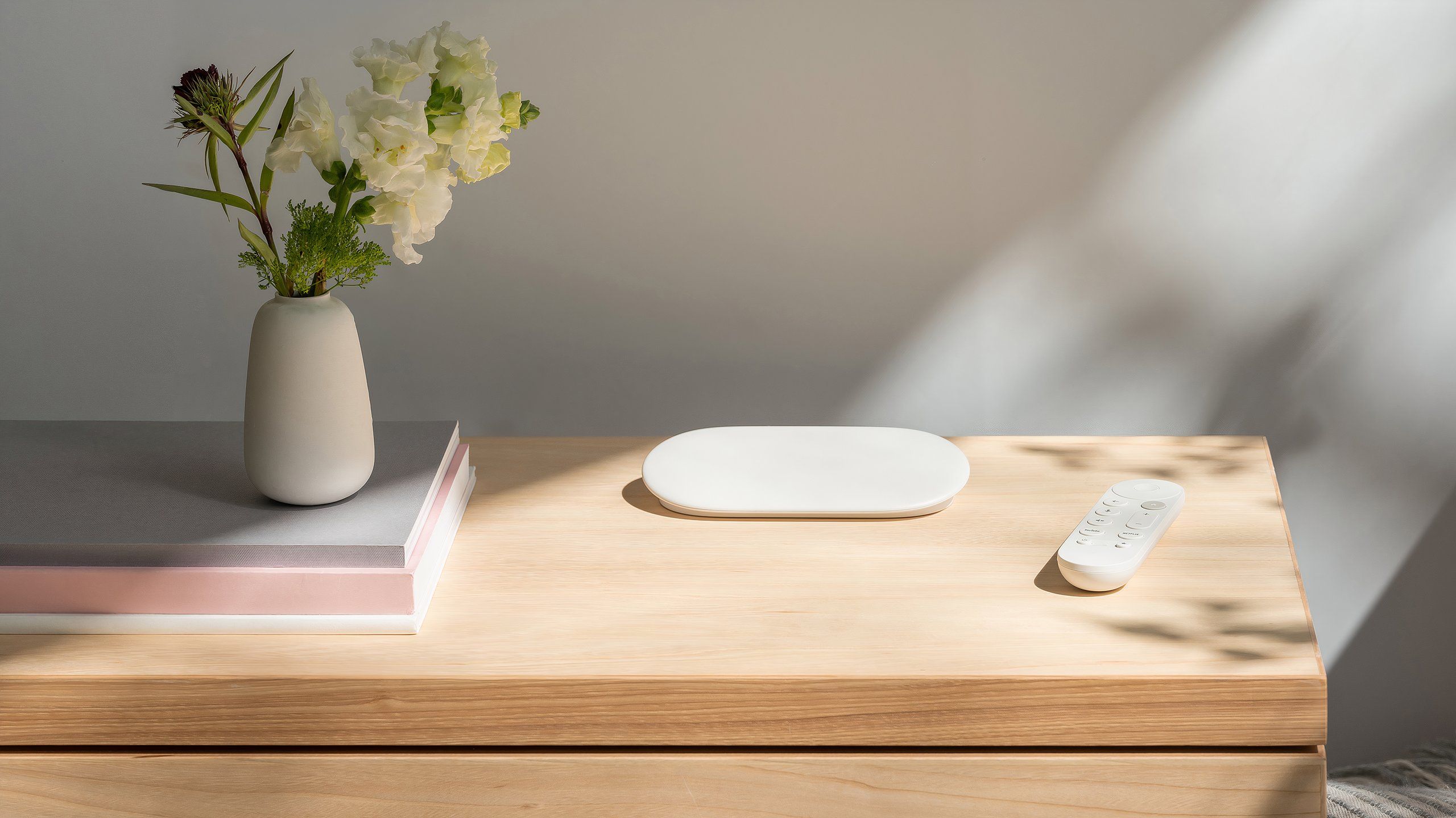 A Google TV Streamer on a table in the sunlight. 