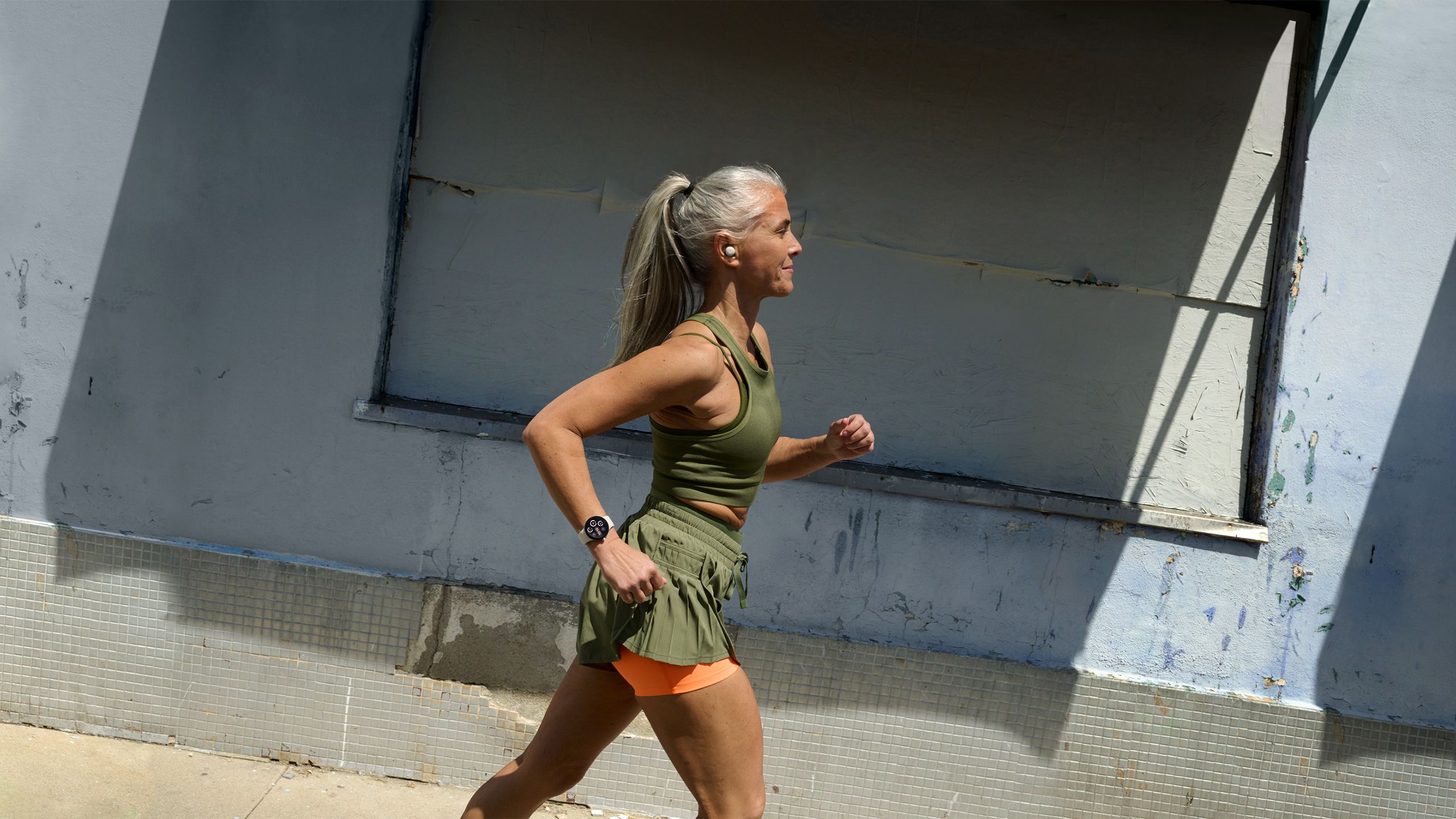 A woman runs in front of a building while wearing the Google Pixel Watch 3. 