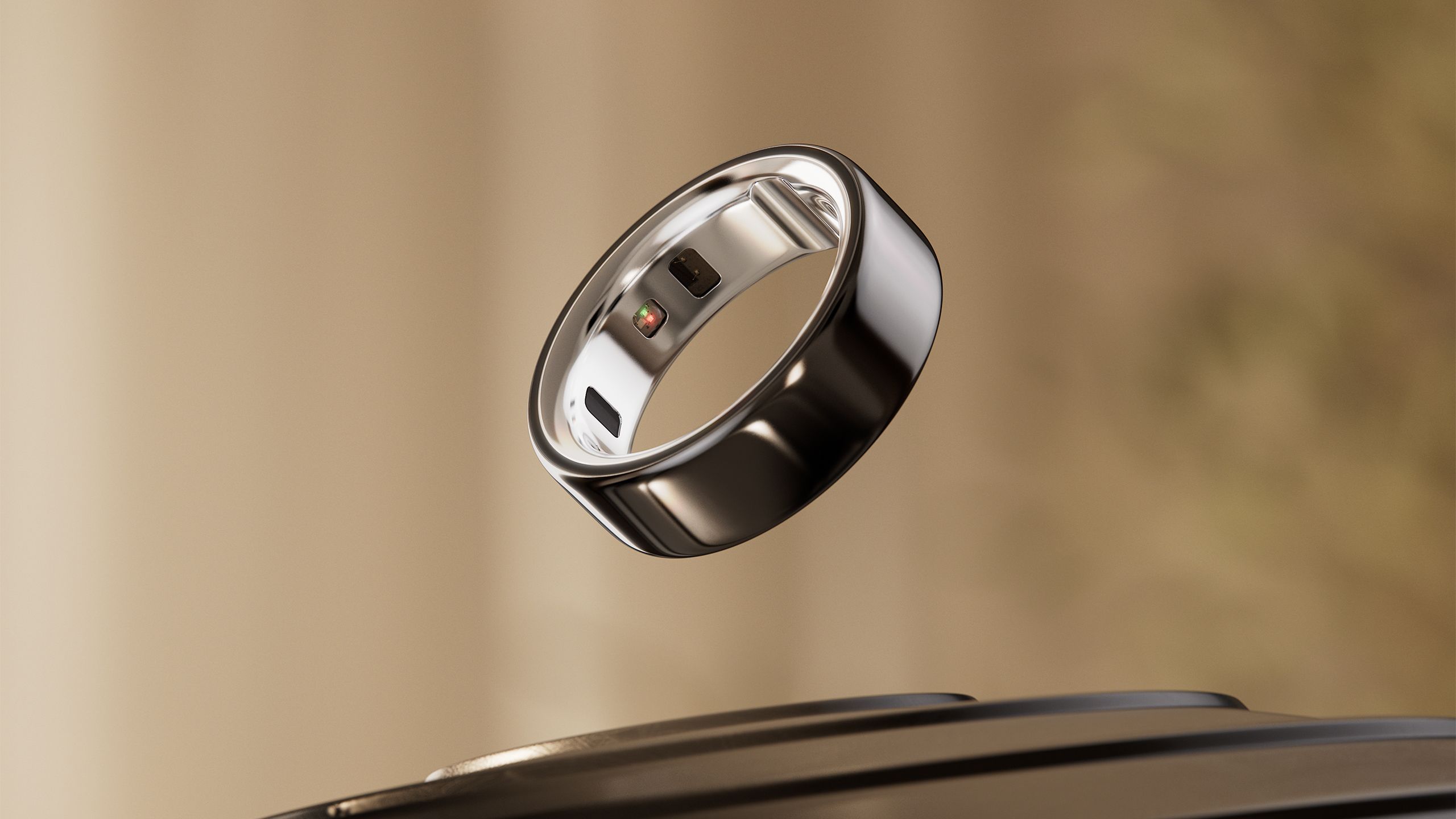 The Oura RIng 4 is floating above a black surface. 