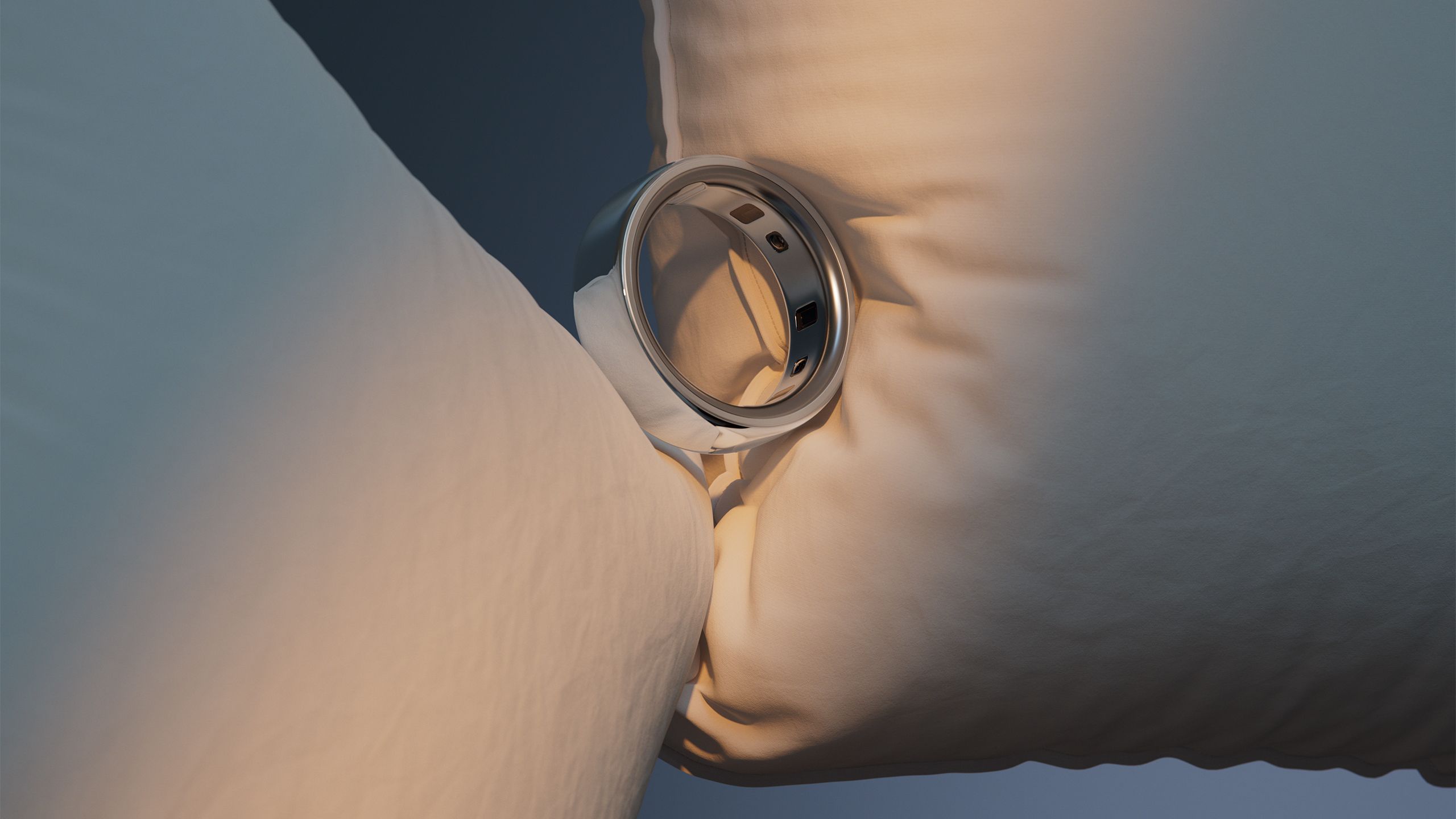 The silver Oura Ring 4 is balanced between two pillows. 