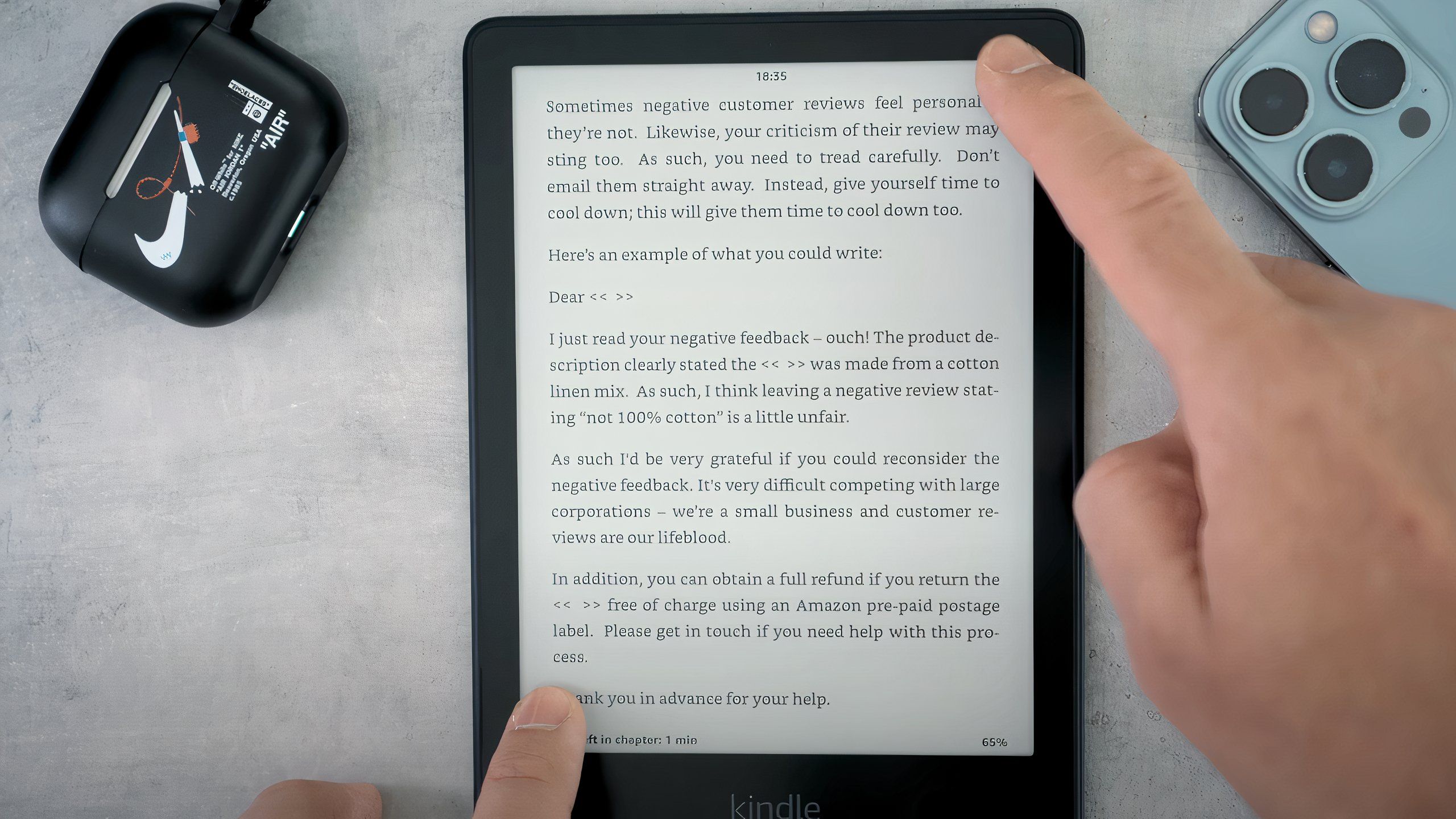 Two fingers pressing on the corner of a Kindle Paperwhite to take a screenshot.