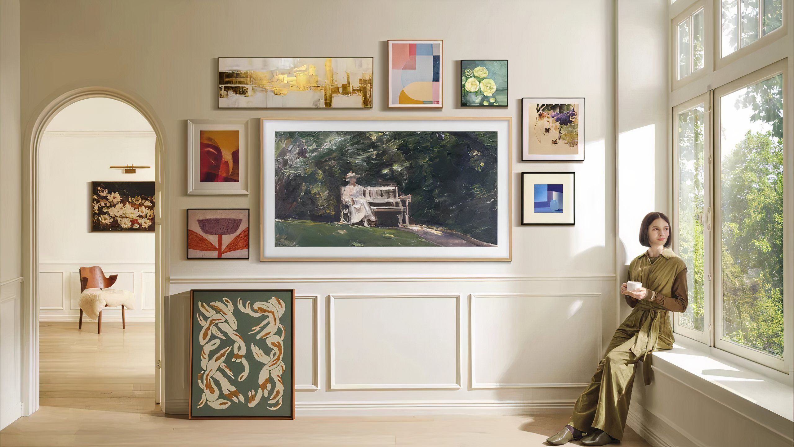 A large TV shaped like a photo frame on a wall surrounded by art.