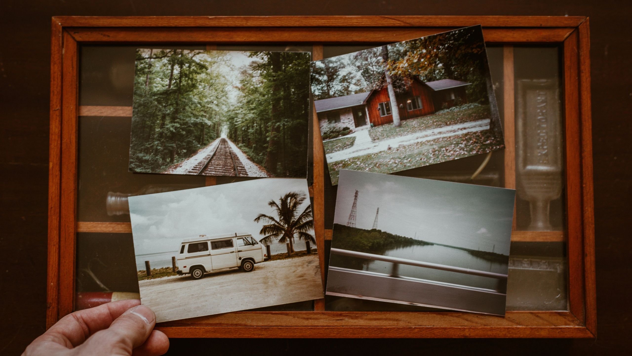 Retro looking photographs of train tracks, a van, a cabin, and a bridge. 