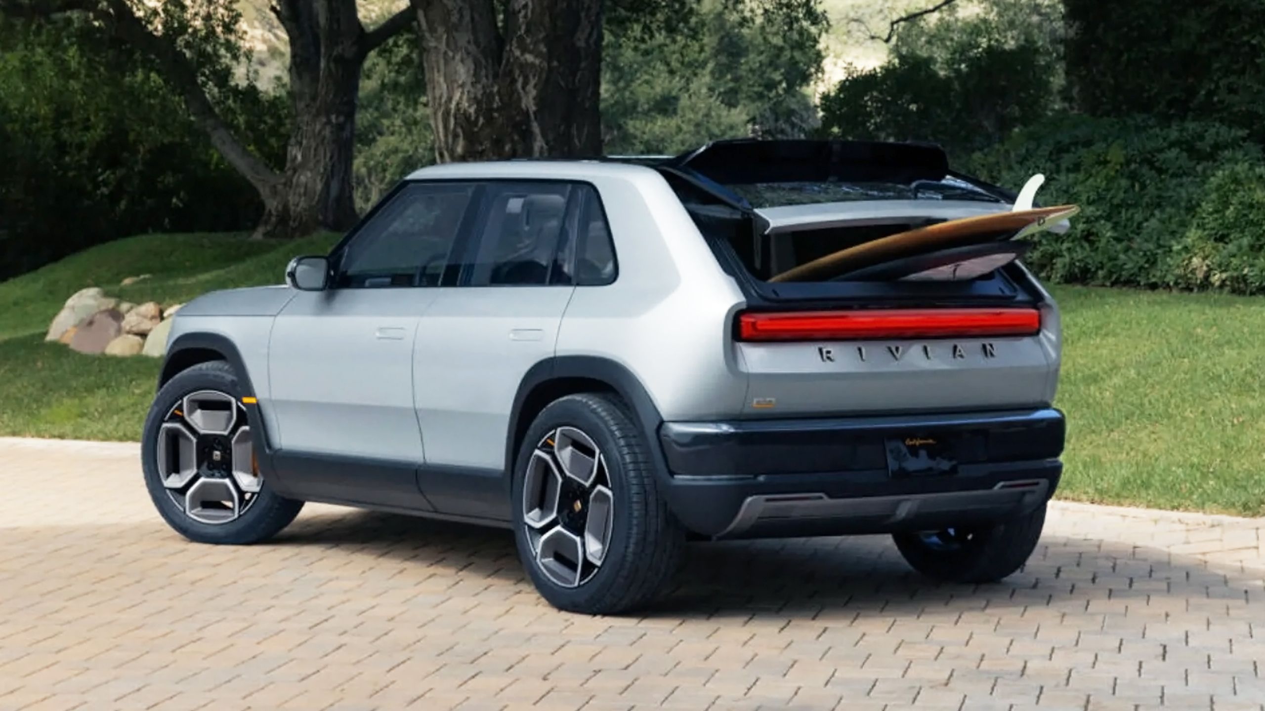 A Rivian R3 with surfboards popping out of its trunk.