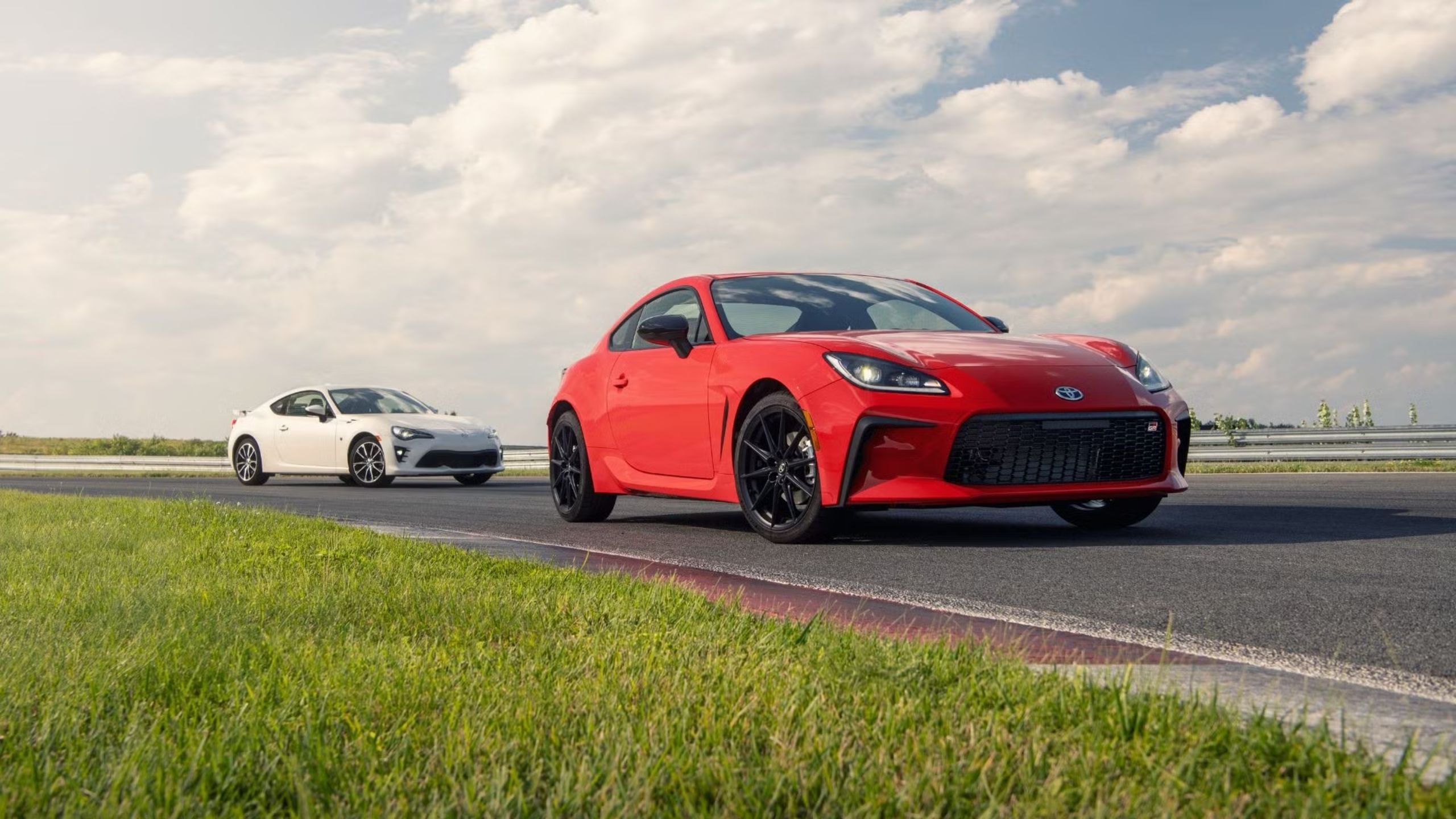 Image of past and present Toyota GR86 parked on a race track.
