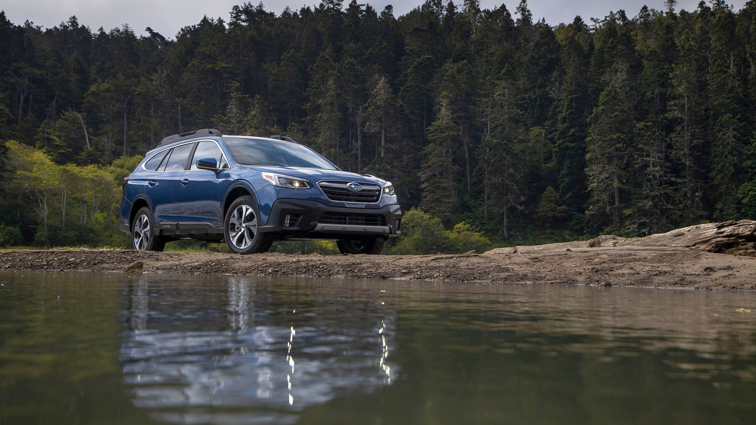 A blue 2020 Subaru Outback parked next to a lake.