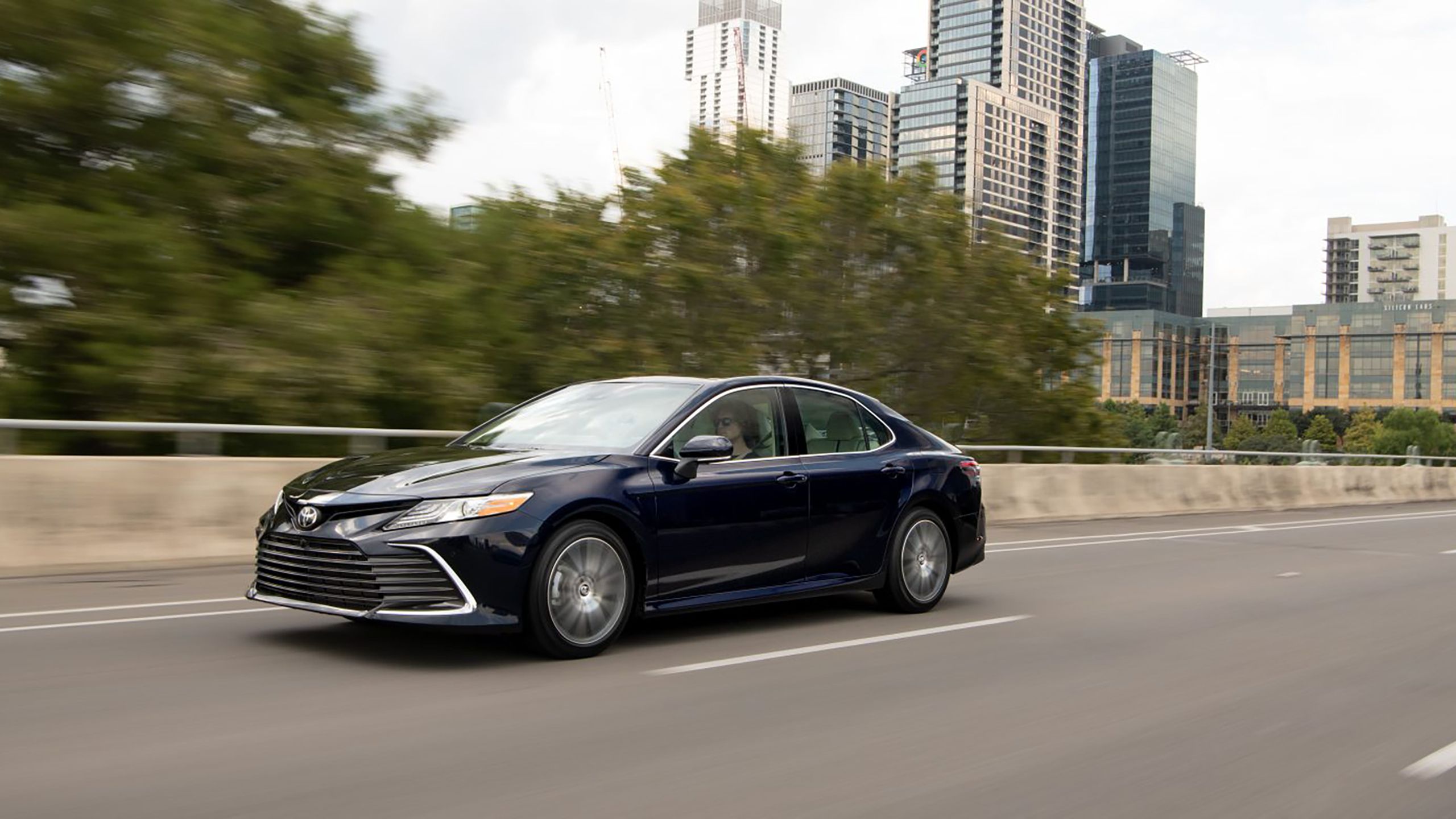 A dark colored 2021 Toyota Camry driving on the freeway