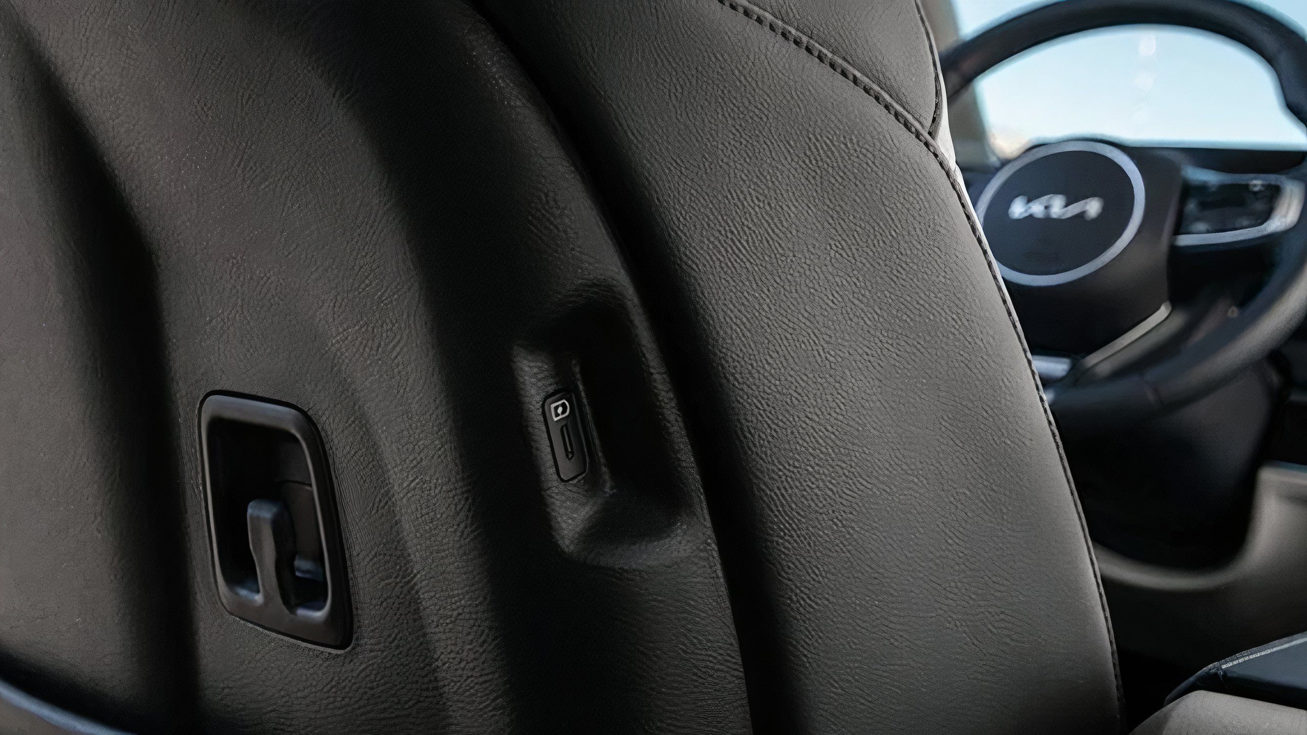 A Kia rear seat charging port mounted on the side of the driver's seat. 