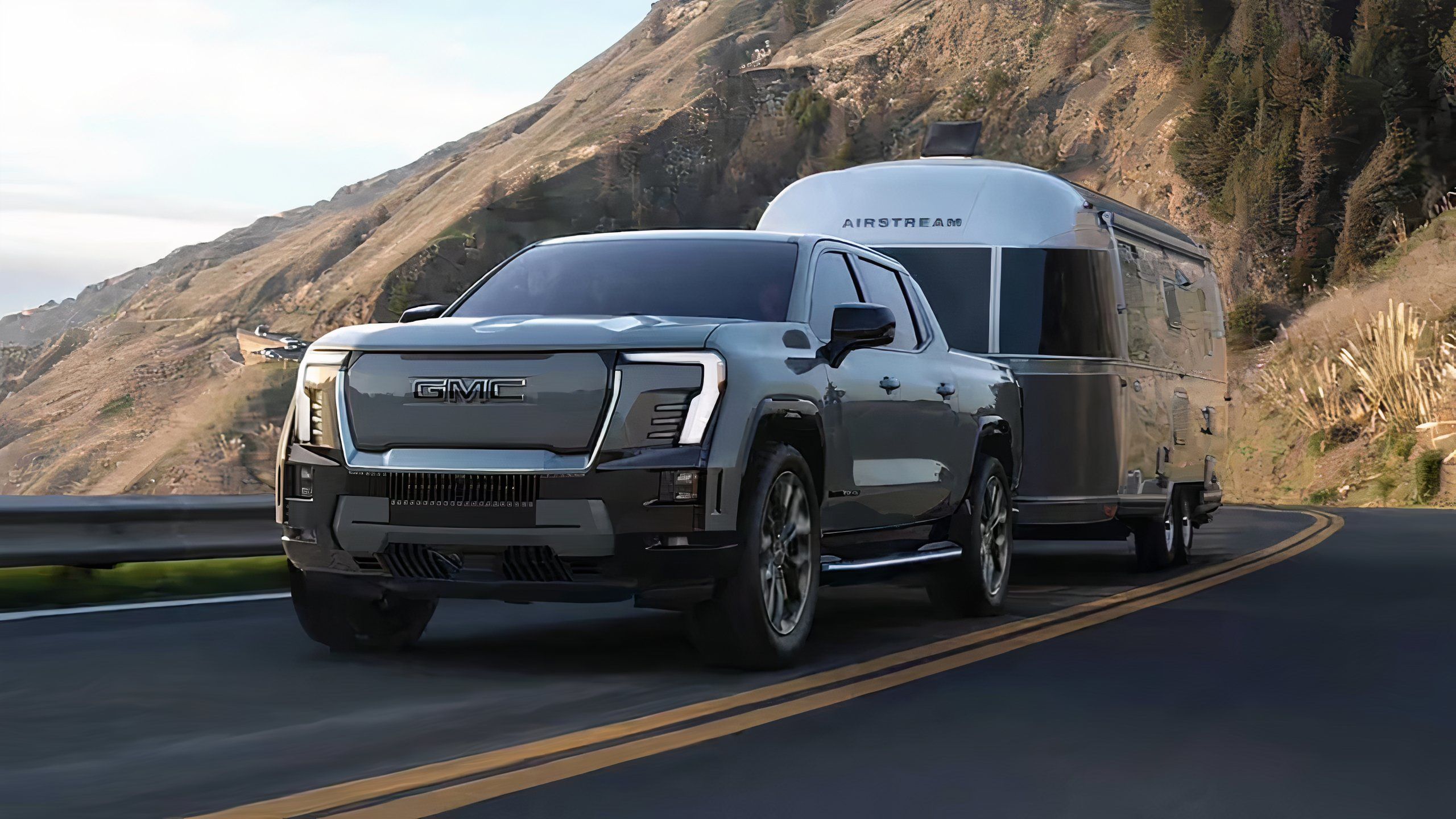 A still photo of a 2024 GMC Sierra EV towing a camper trailer. 