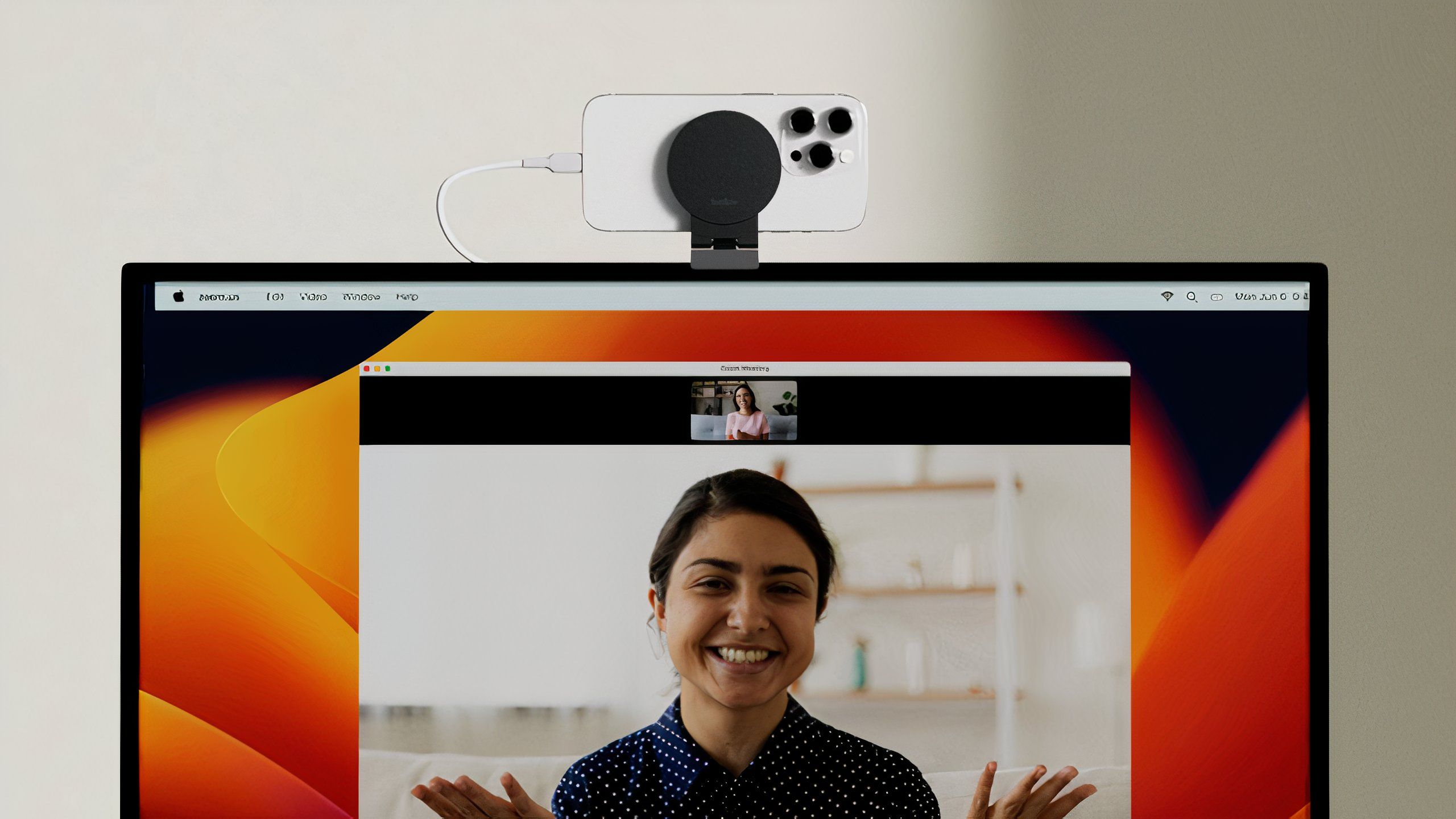 An Apple Studio Display with an iPhone mounted on a stand sitting on top.