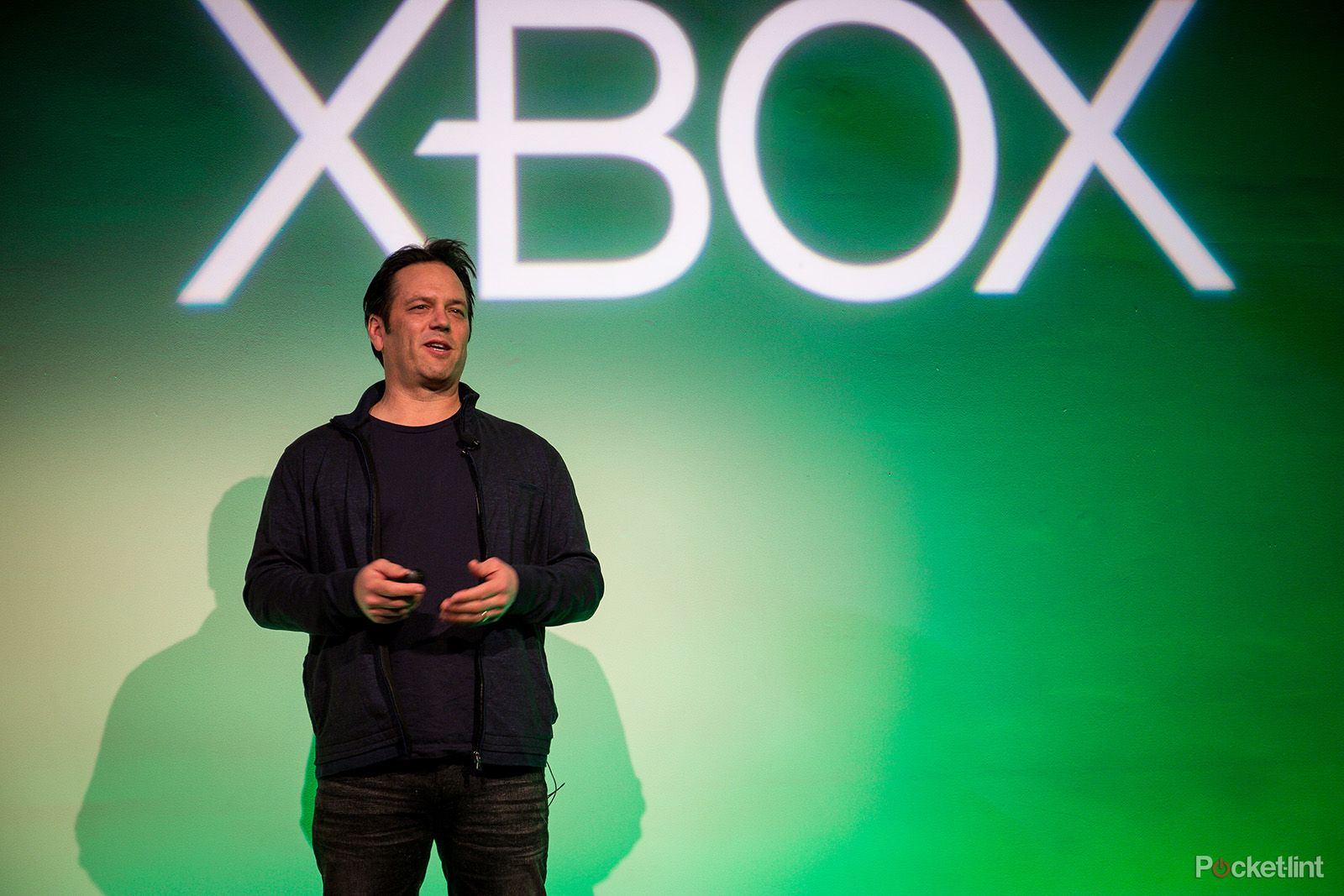 Xbox boss phil spencer stood on stage in front of Xbox logo
